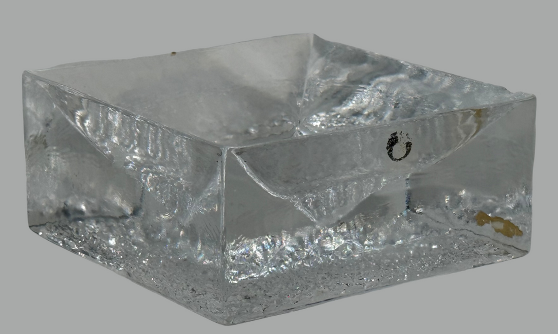 Clear glass block with a star-shaped cutout on a white surface