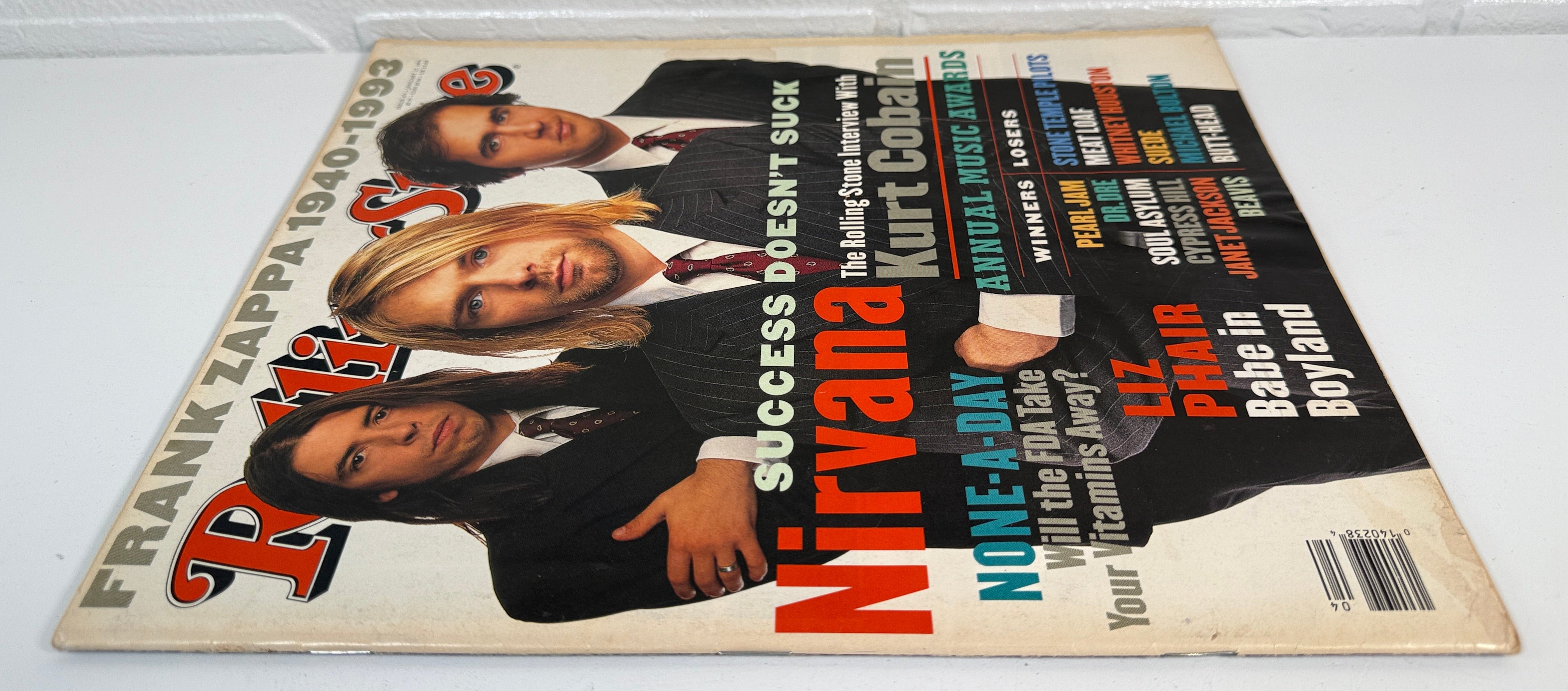 Magazine cover featuring Nirvana on a white surface with a brick wall background