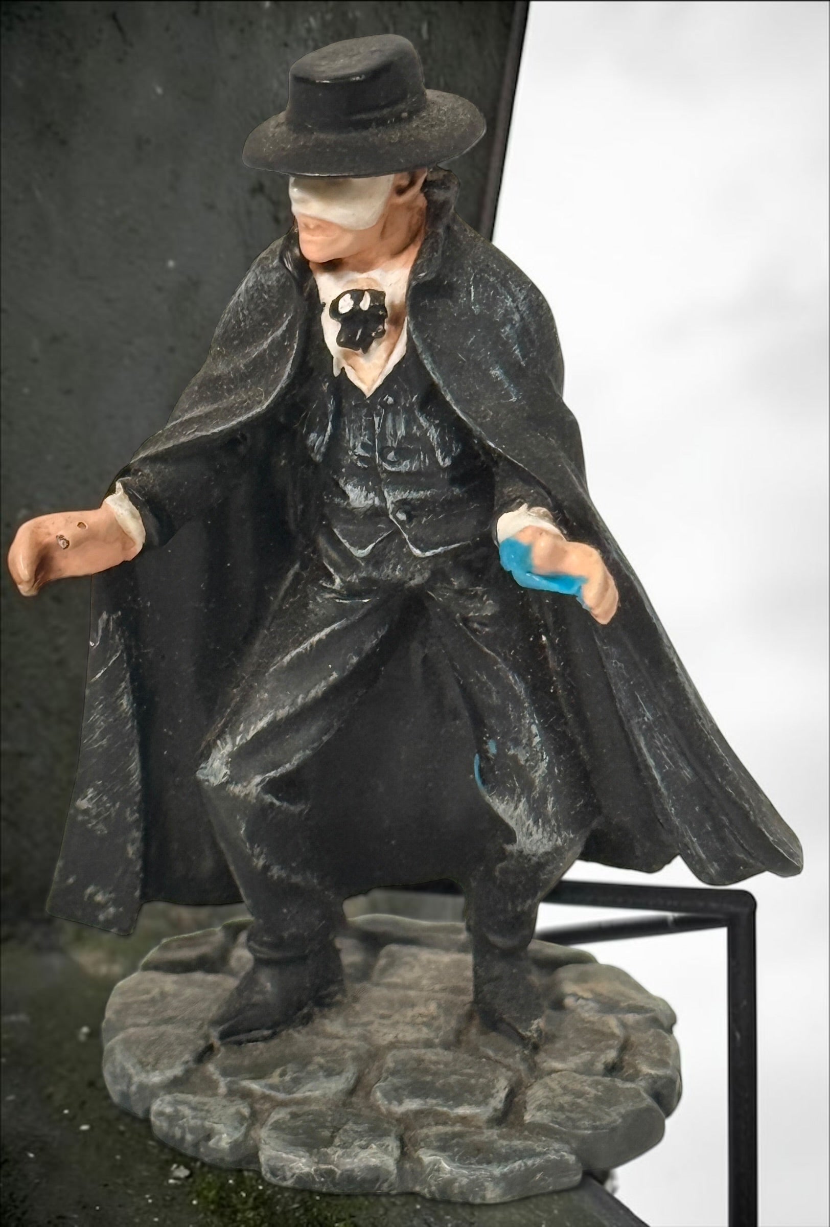 Vintage Phantom of the Opera–style resin figurine with black cape and cobblestone base. Damaged with missing accessories; sold as-is.