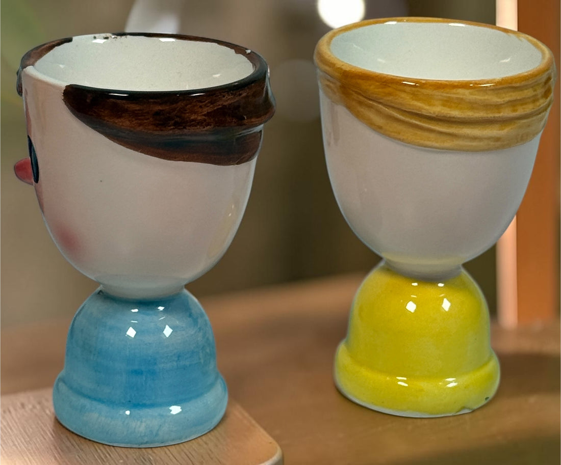 Vintage Japanese ceramic boy and girl egg cups with original colourful yarn egg cozy hats. Charming 1960s–70s novelty kitchenware pair.