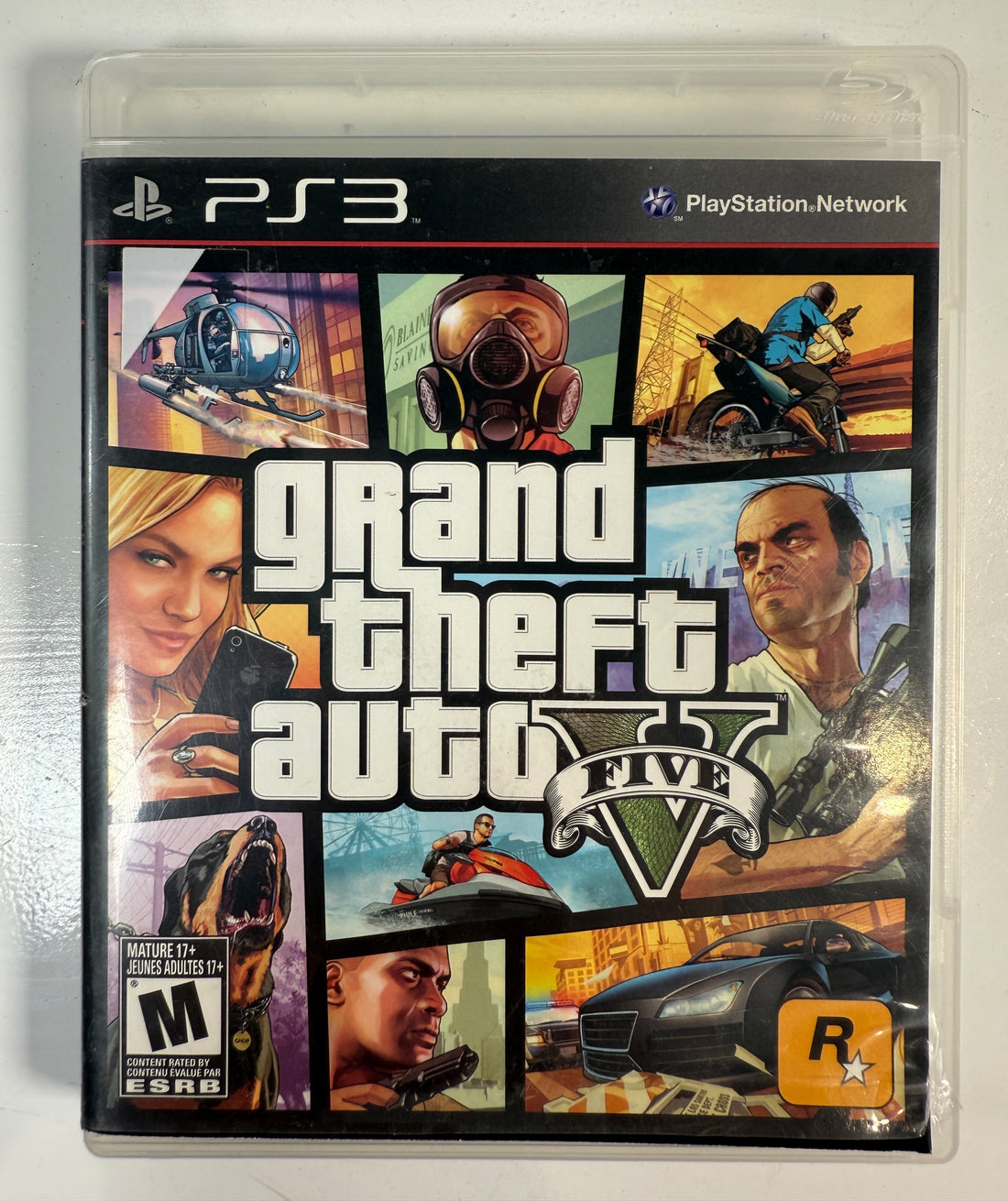PlayStation 3 game case for 'Grand Theft Auto V' with various characters and scenes.