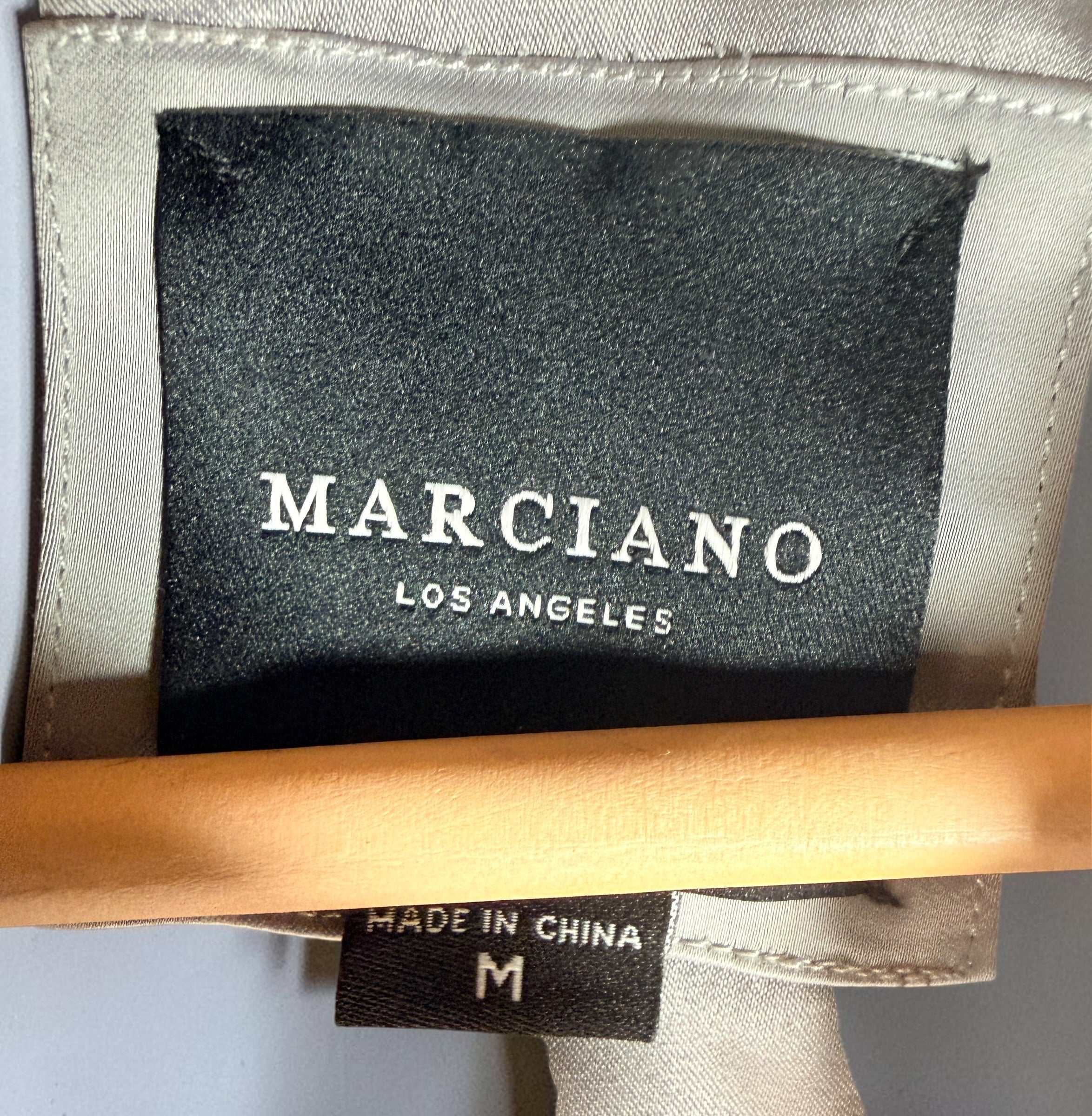 Shop the Marciano Limitless bomber jacket in silver-grey satin, size M. Original tags attached, zip pockets and ribbed trim. Minor marks disclosed.