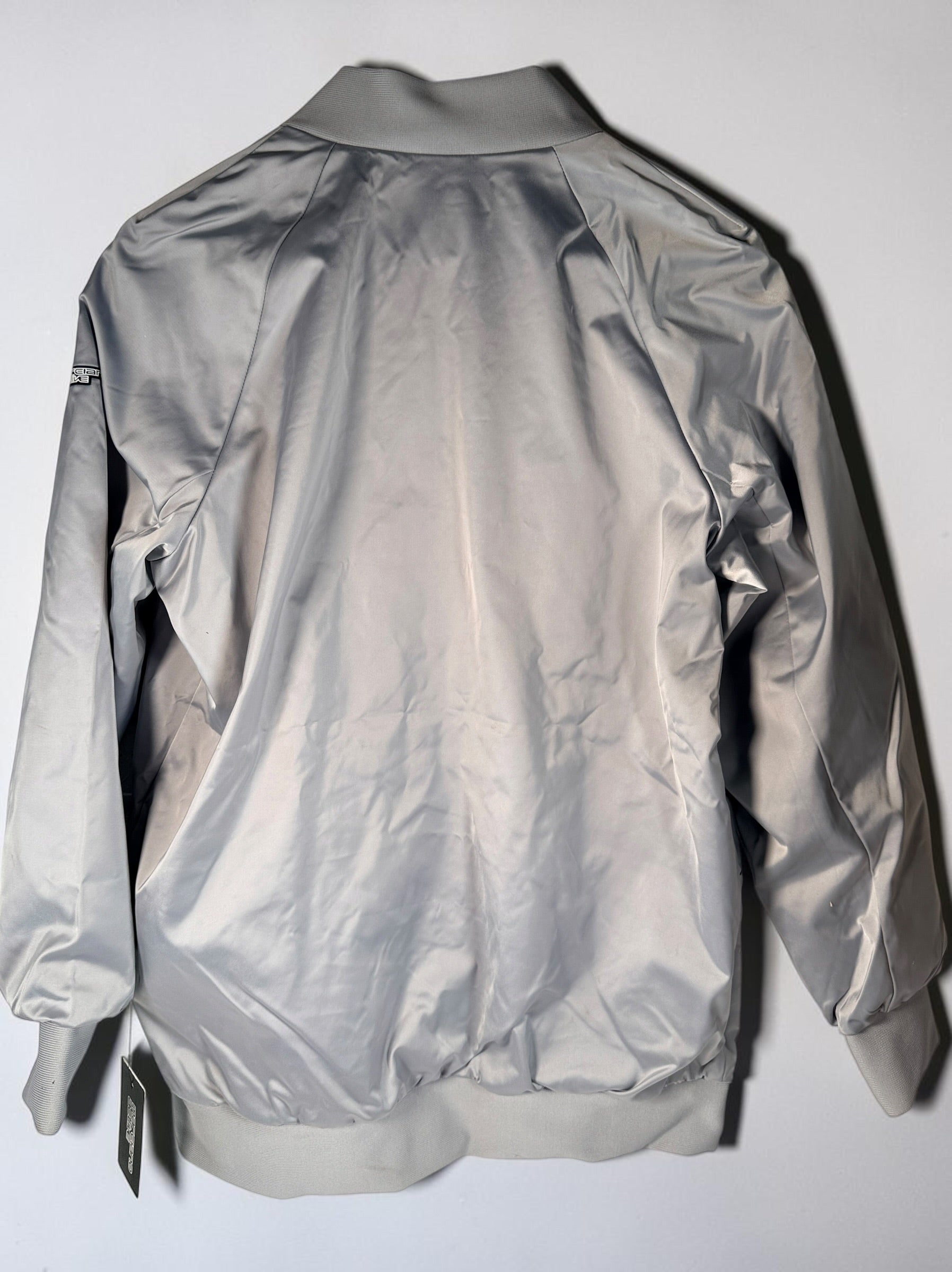 Shop the Marciano Limitless bomber jacket in silver-grey satin, size M. Original tags attached, zip pockets and ribbed trim. Minor marks disclosed.