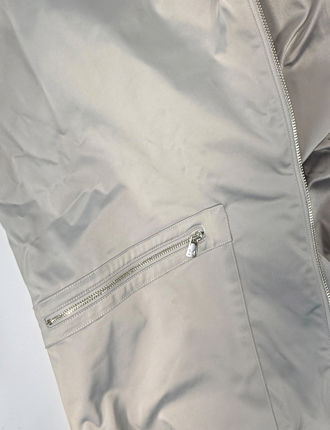 Shop the Marciano Limitless bomber jacket in silver-grey satin, size M. Original tags attached, zip pockets and ribbed trim. Minor marks disclosed.