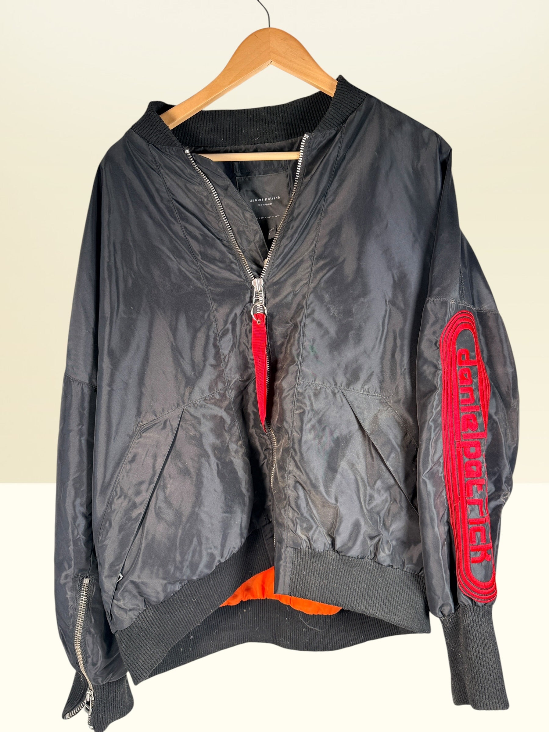 Daniel Patrick Los Angeles oversized black bomber jacket, size L, with orange lining, red embroidered sleeve logo and branded zipper pulls.
