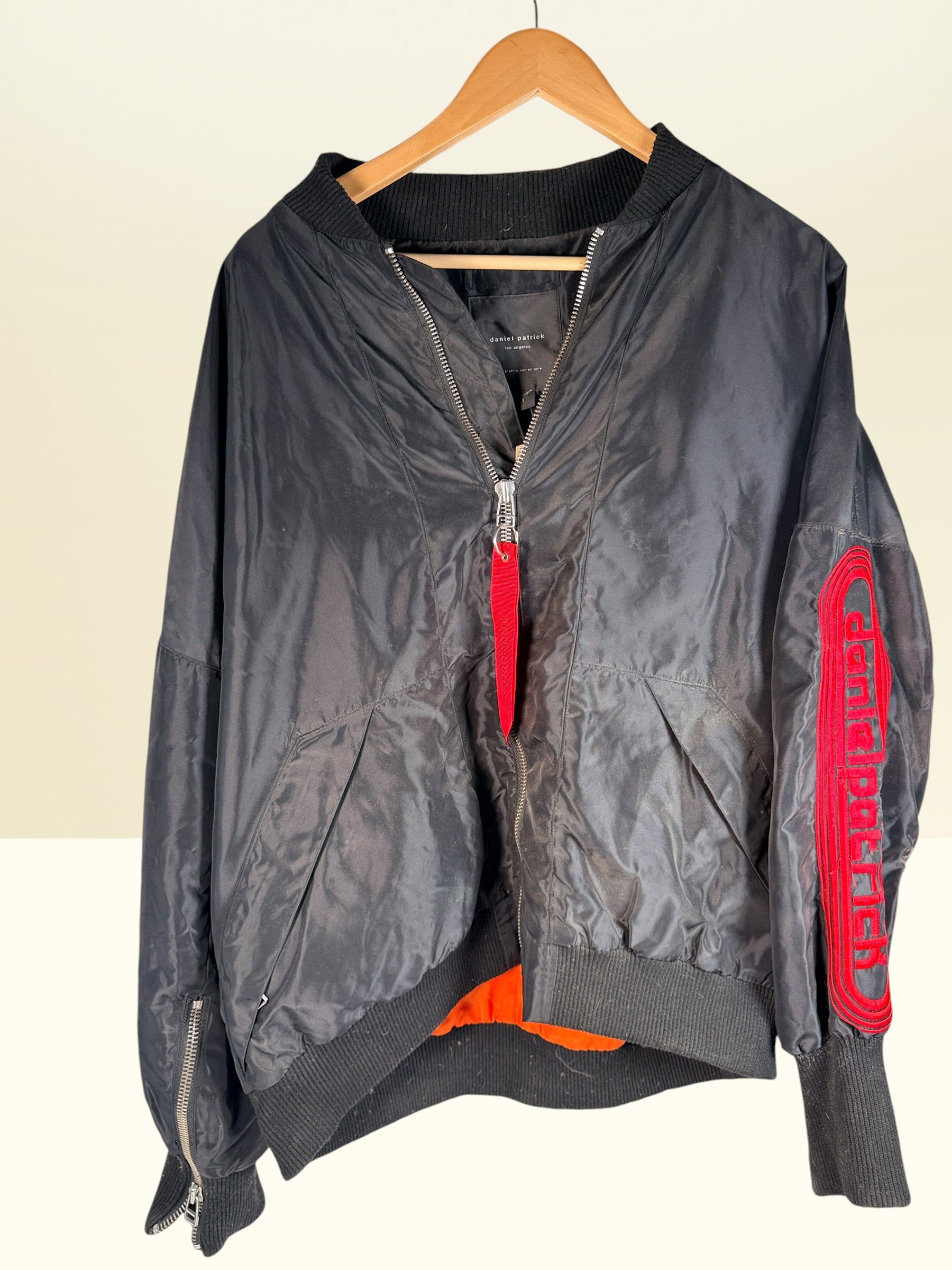 Daniel Patrick Los Angeles oversized black bomber jacket, size L, with orange lining, red embroidered sleeve logo and branded zipper pulls.