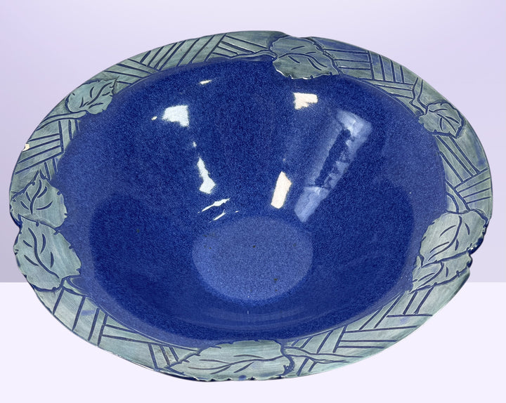 Signed studio pottery bowl with cobalt blue glaze and leaf rim detail. Handmade decorative ceramic centerpiece bowl ideal for modern rustic home decor.
