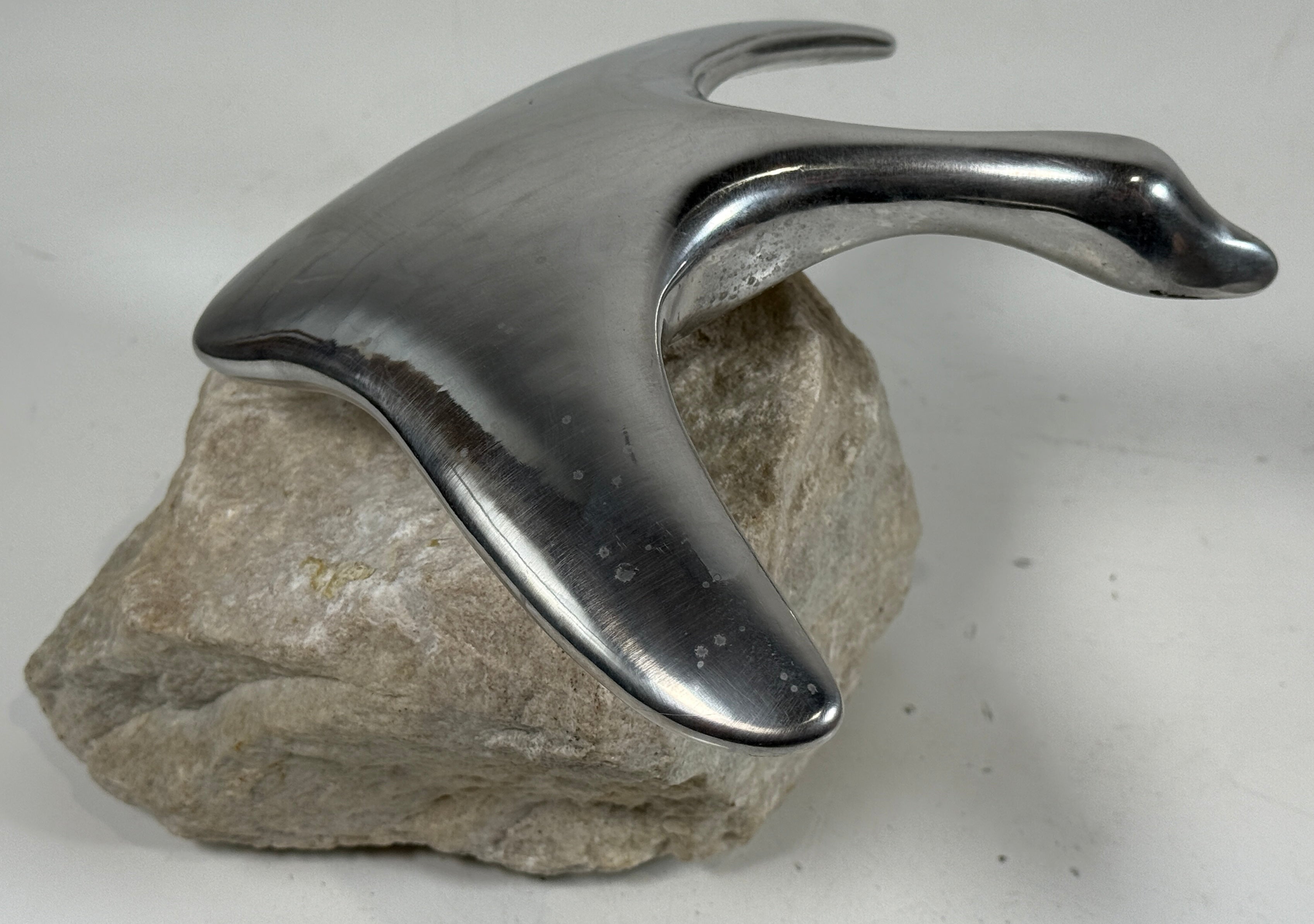 Metallic sculpture on a stone base against a white background