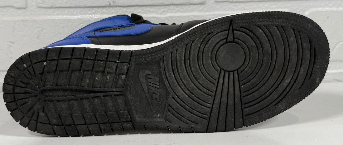 Close-up of a black and blue sneaker sole with a brand logo on a light gray background