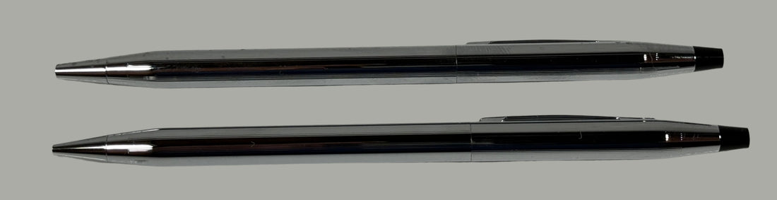 Two black pens with silver accents on a light gray surface