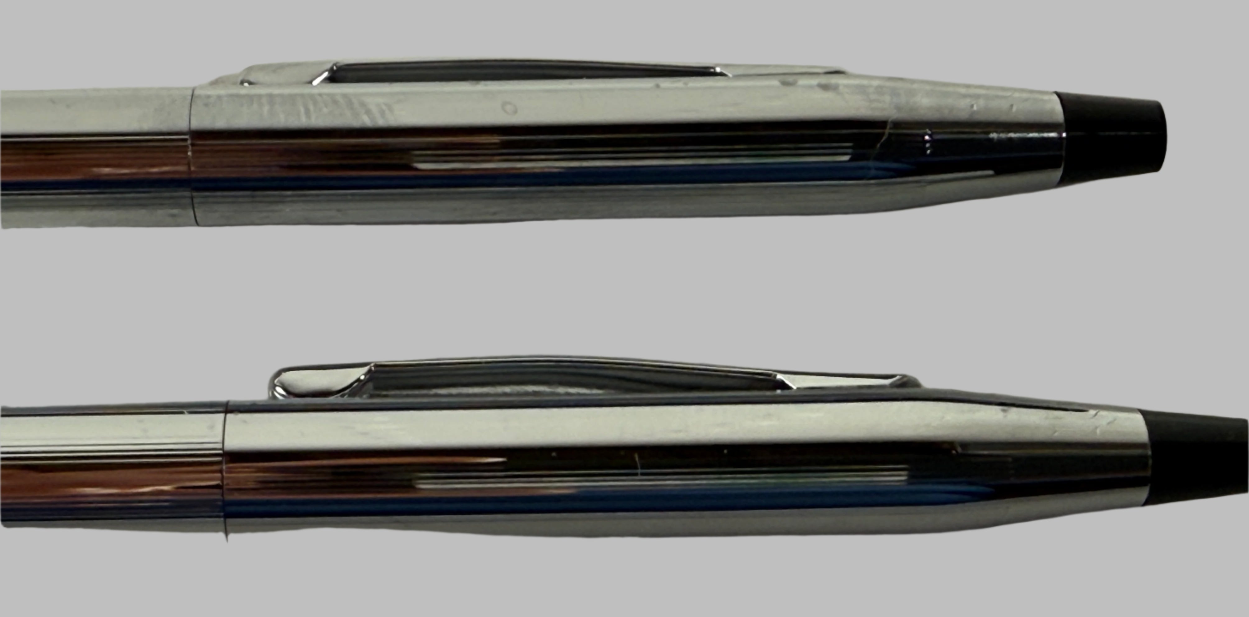 Two pens with metallic and black accents on a textured surface