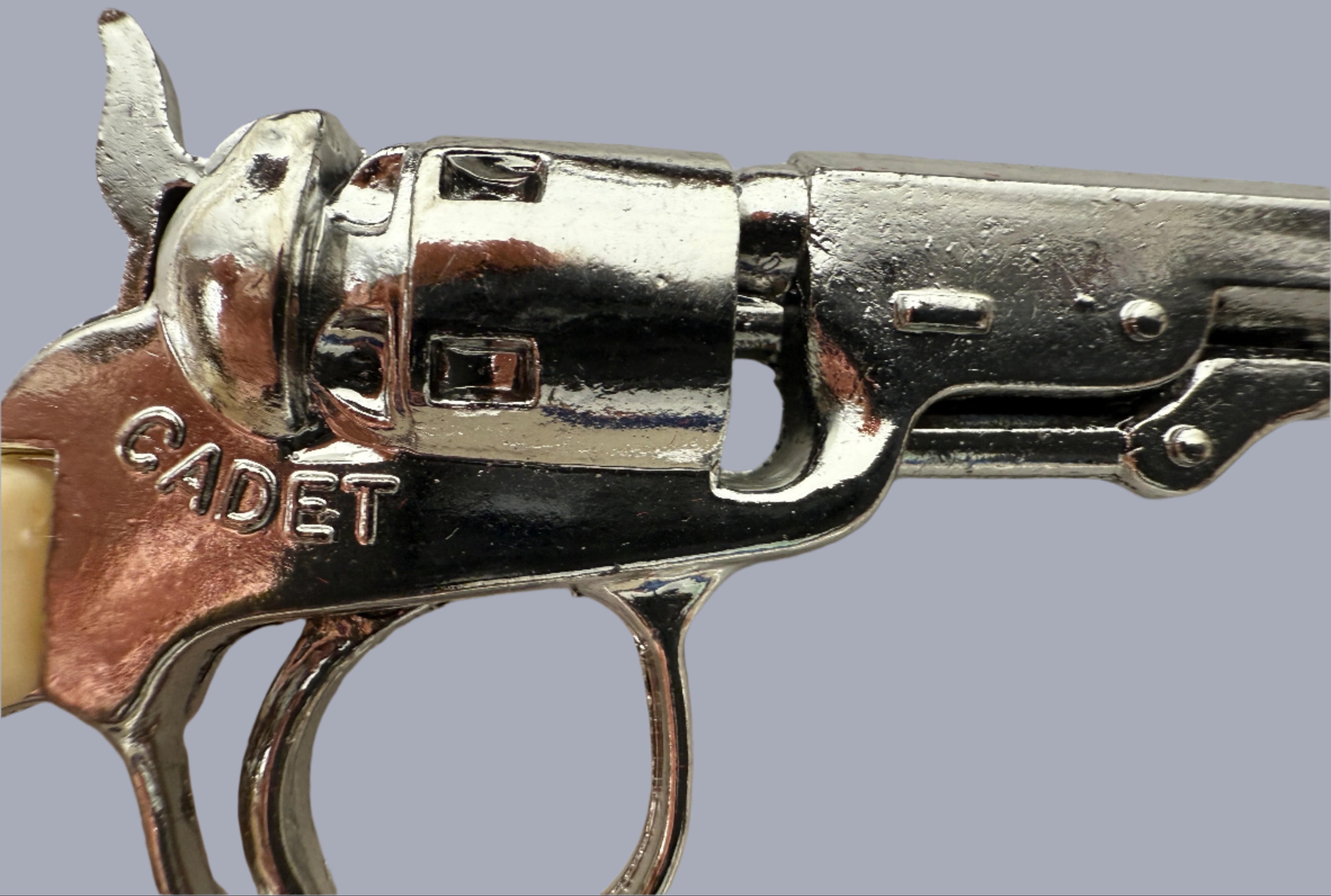 Close-up of a silver revolver with 'Cadet' branding on a light gray background
