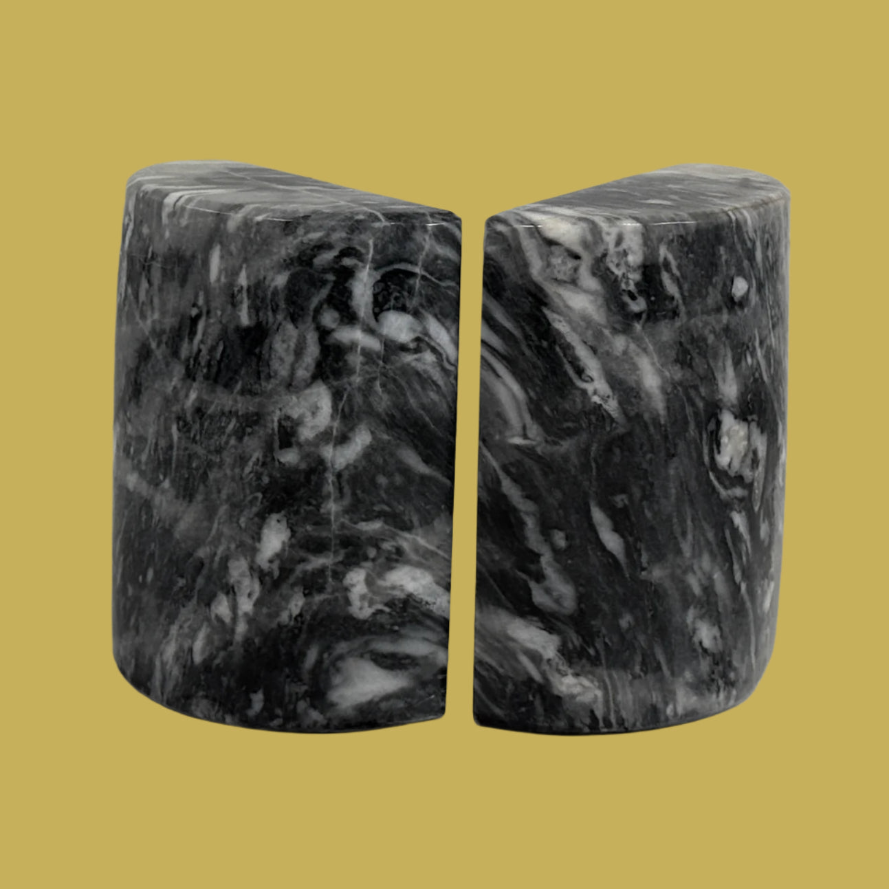 Marble-patterned bookends on a white surface with a light gray brick wall background