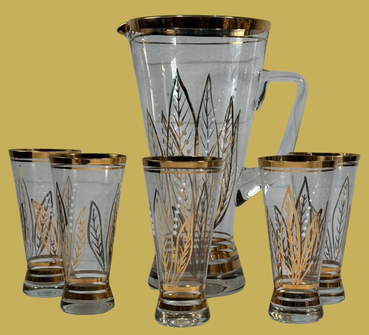 Set of glass pitchers and tumblers with gold and black designs on a white surface.