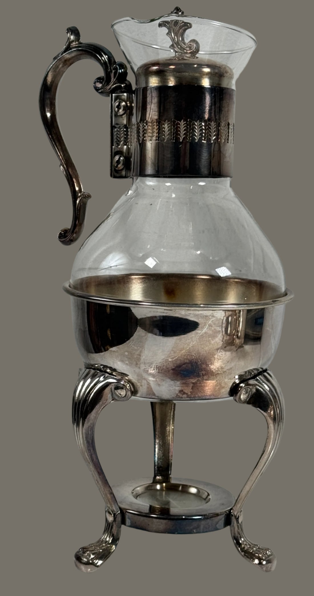 Silver and glass decanter with footed base on a white surface