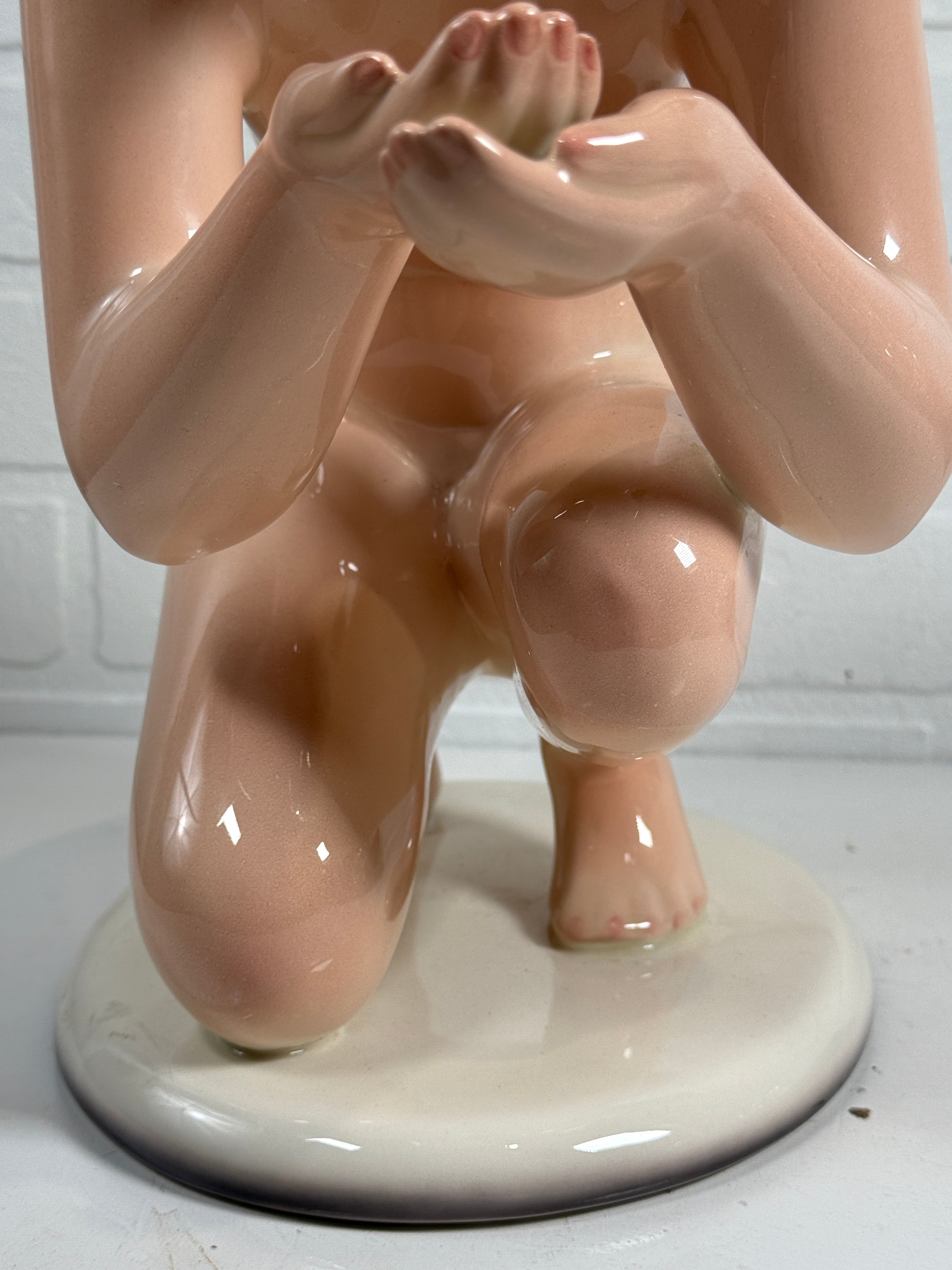 Glossy ceramic sculpture of a reclining figure on a white background
