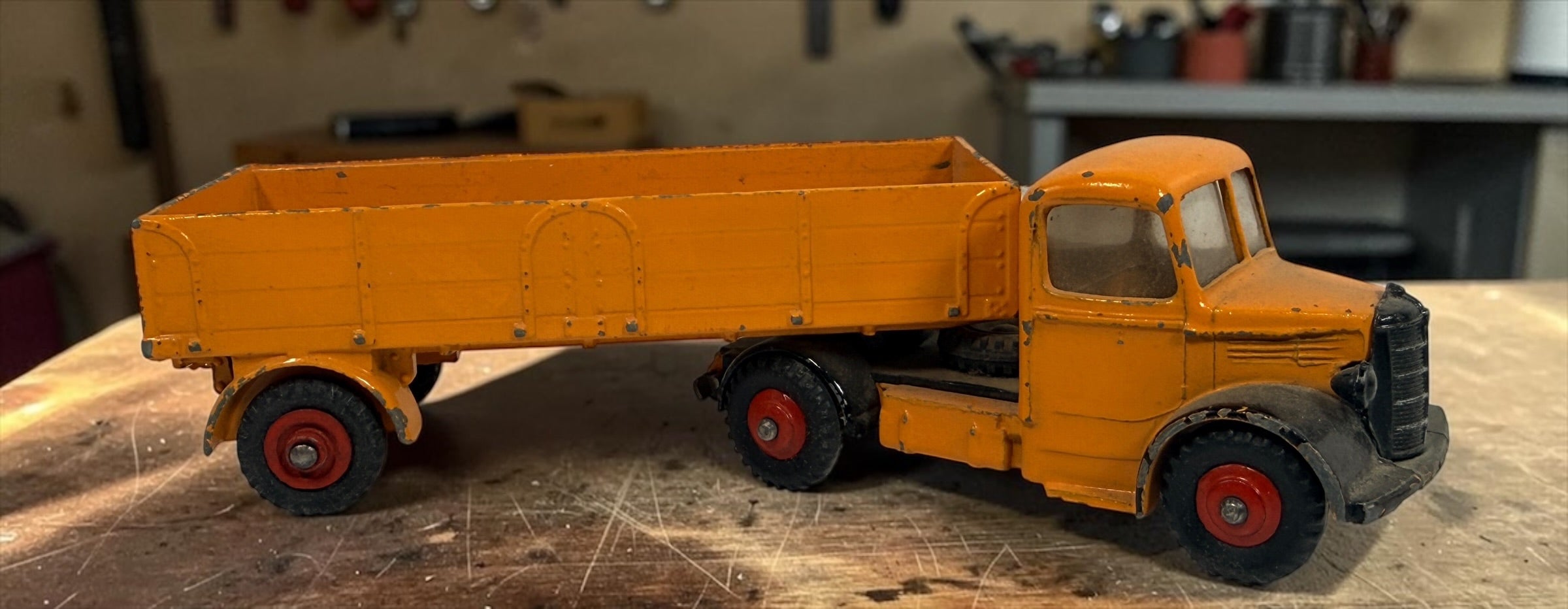 Vintage Dinky Toys Bedford articulated lorry by Meccano Ltd., England. Original die-cast truck and trailer in orange with classic red wheels.