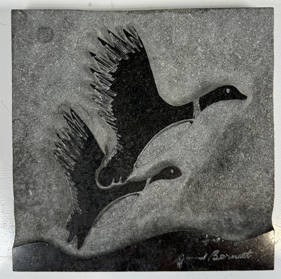 Black and white carving of two birds on a textured stone background
