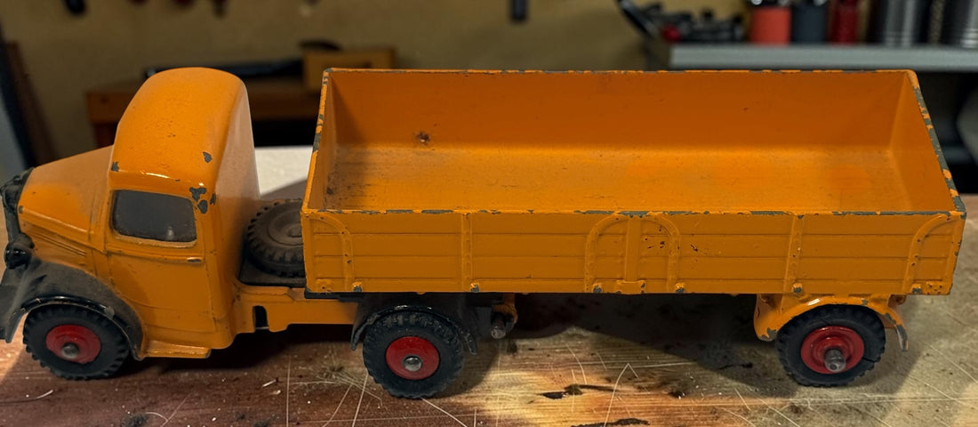 Vintage Dinky Toys Bedford articulated lorry by Meccano Ltd., England. Original die-cast truck and trailer in orange with classic red wheels.