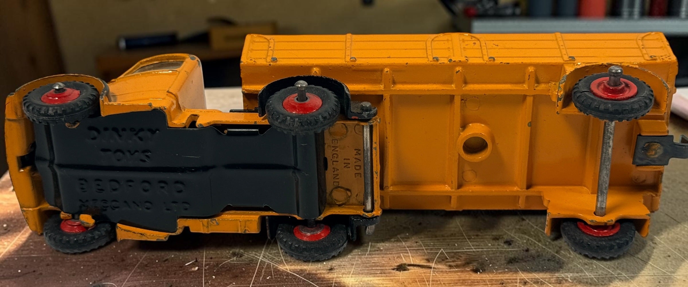 Vintage Dinky Toys Bedford articulated lorry by Meccano Ltd., England. Original die-cast truck and trailer in orange with classic red wheels.