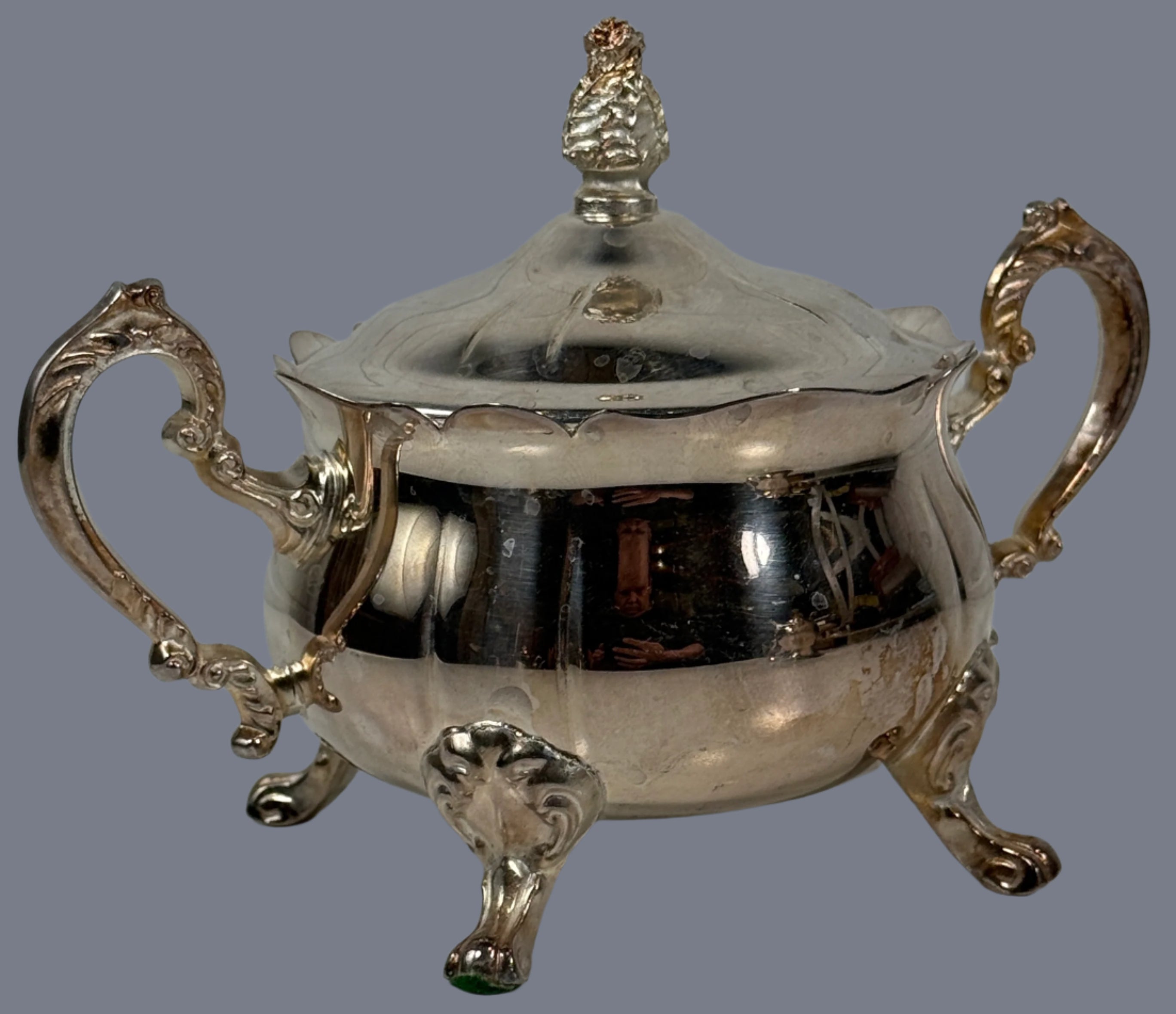 Silver sugar bowl with decorative handles and lid on a white background