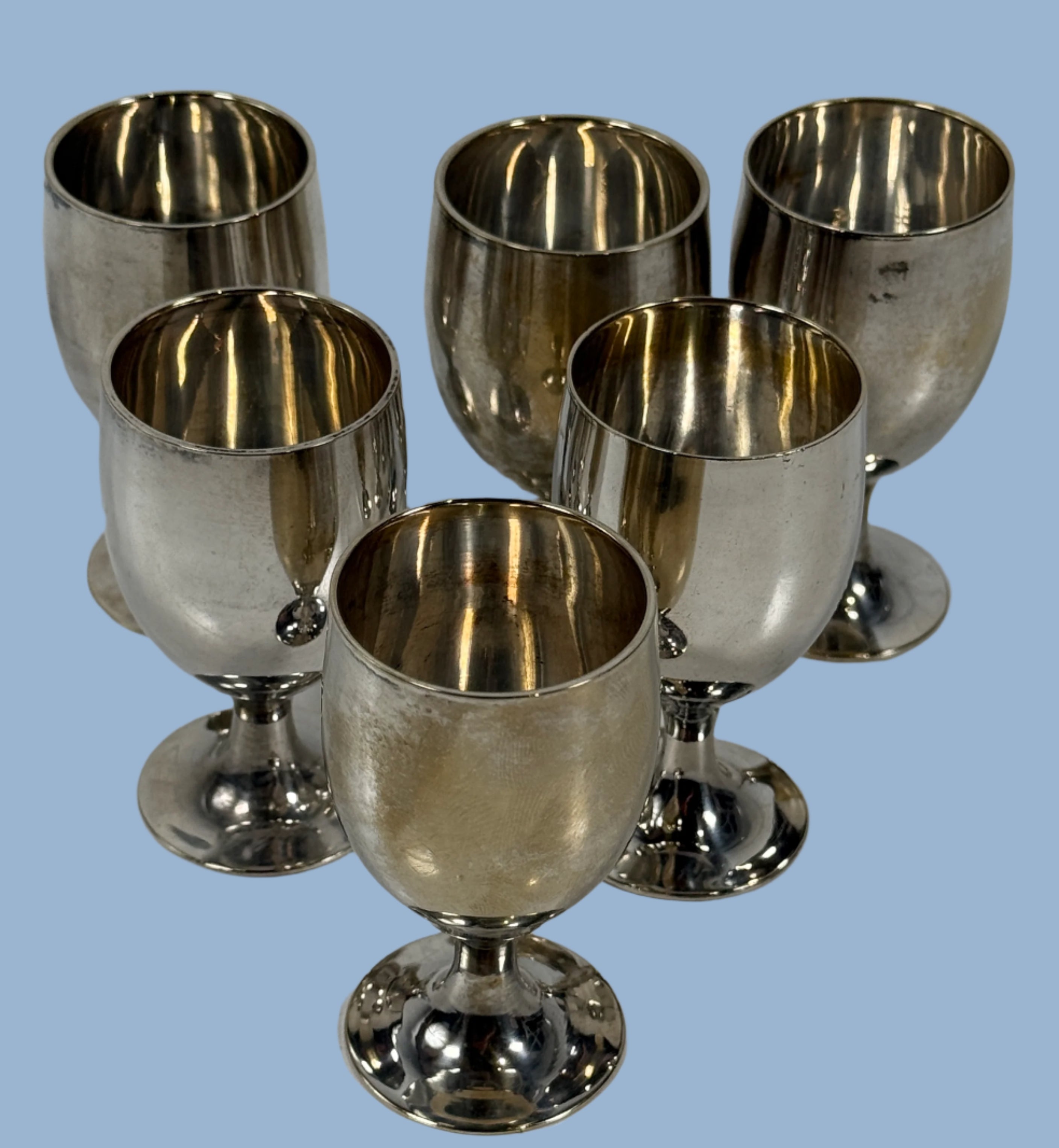 Set of six silver goblets on a white surface