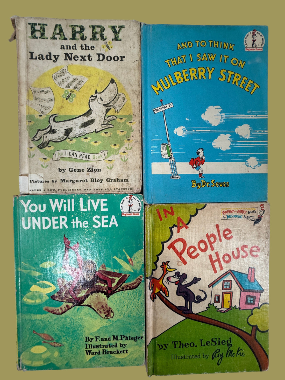 Four vintage children's books stacked on a white surface