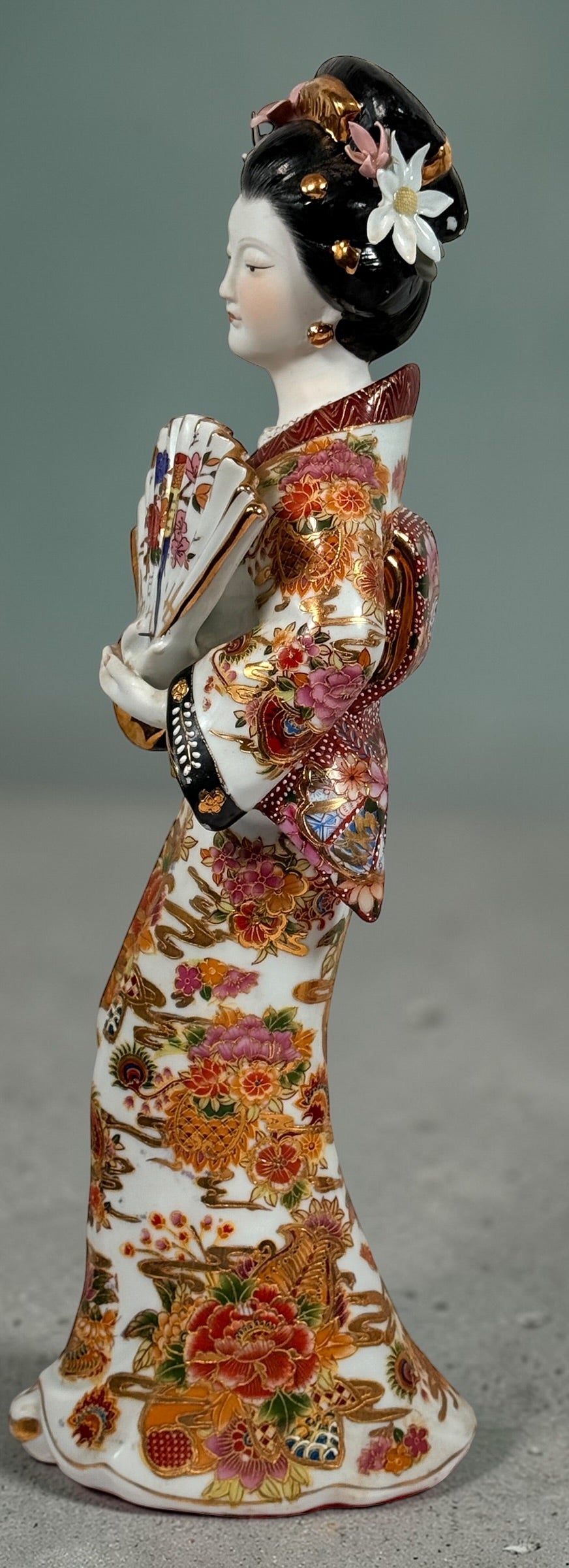 Vintage Japanese porcelain geisha figurine with hand-painted florals and raised gilt moriage detail. Elegant mid-century decorative display piece