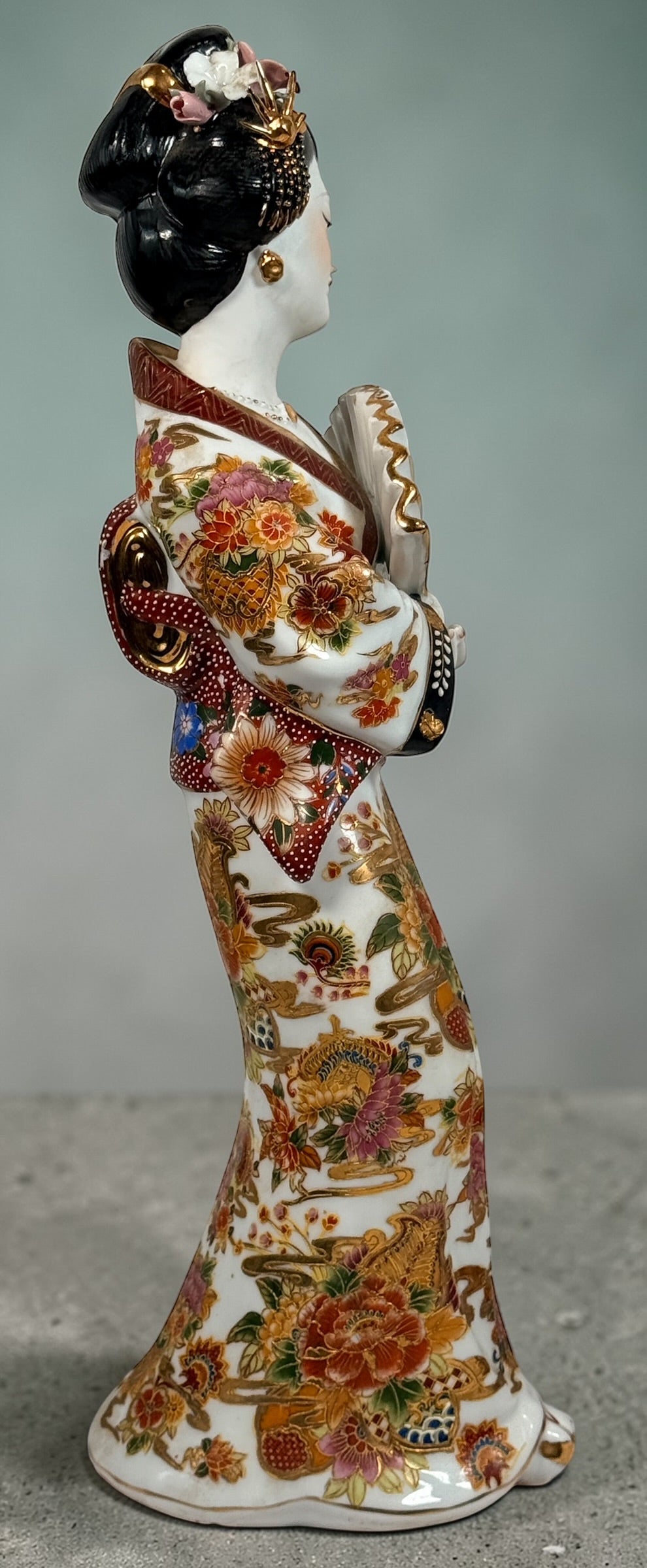 Vintage Japanese porcelain geisha figurine with hand-painted florals and raised gilt moriage detail. Elegant mid-century decorative display piece
