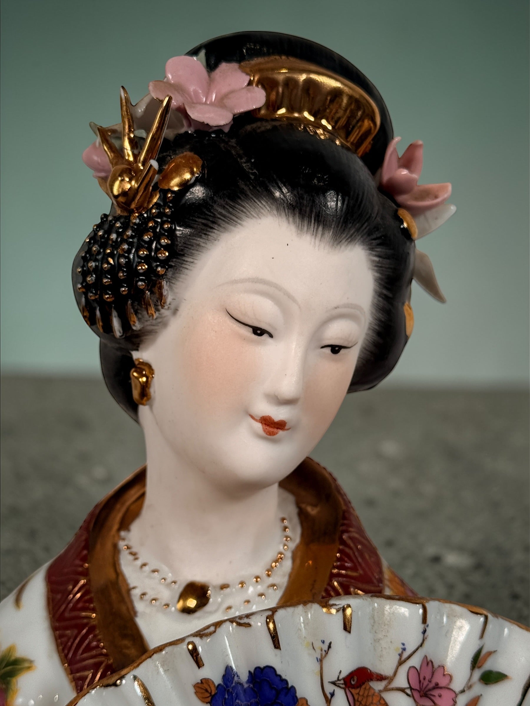 Vintage Japanese porcelain geisha figurine with hand-painted florals and raised gilt moriage detail. Elegant mid-century decorative display piece