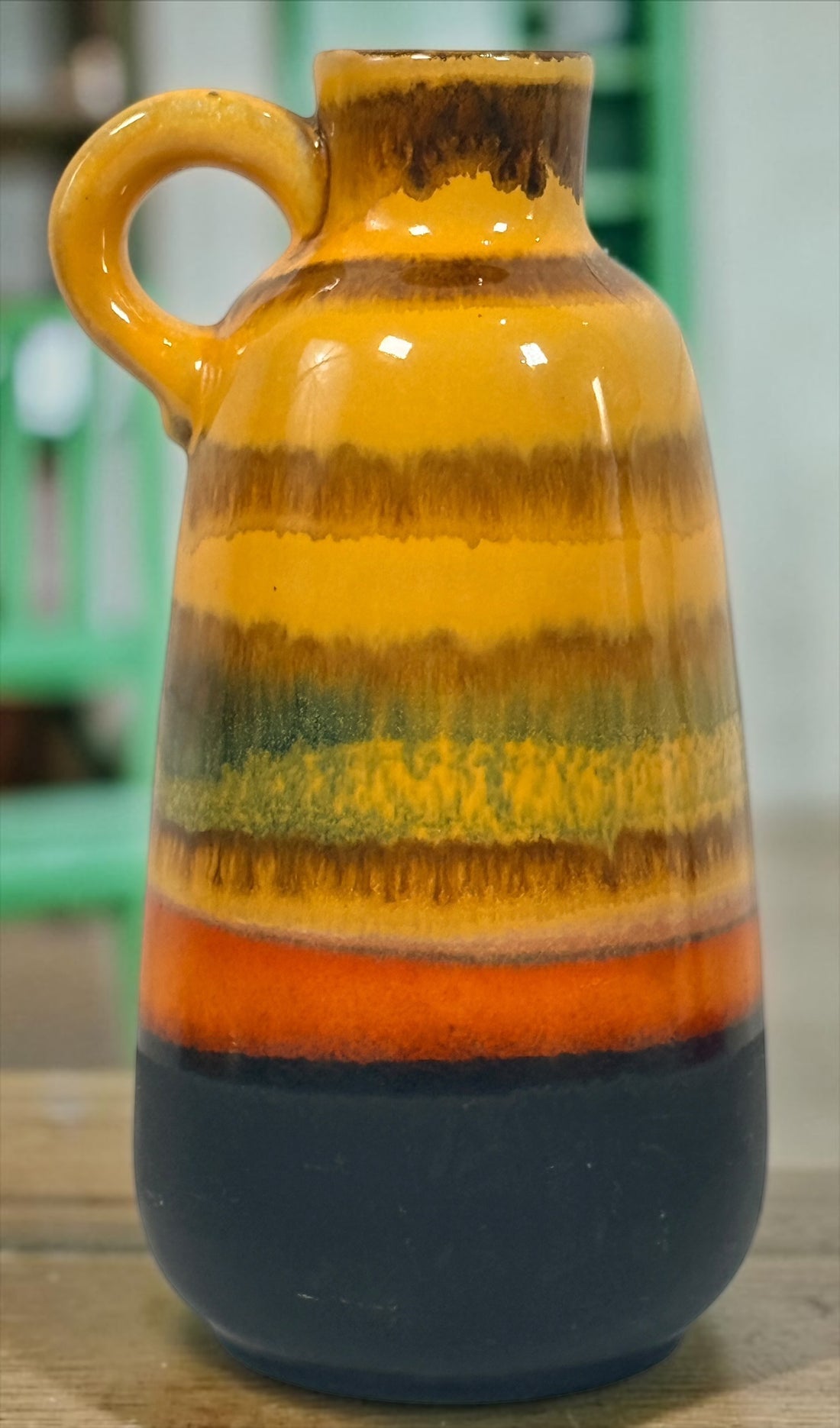 Vintage 1970s West German pottery vase marked 153L-20 with loop handle and colourful mustard, orange, green and brown striped glaze.