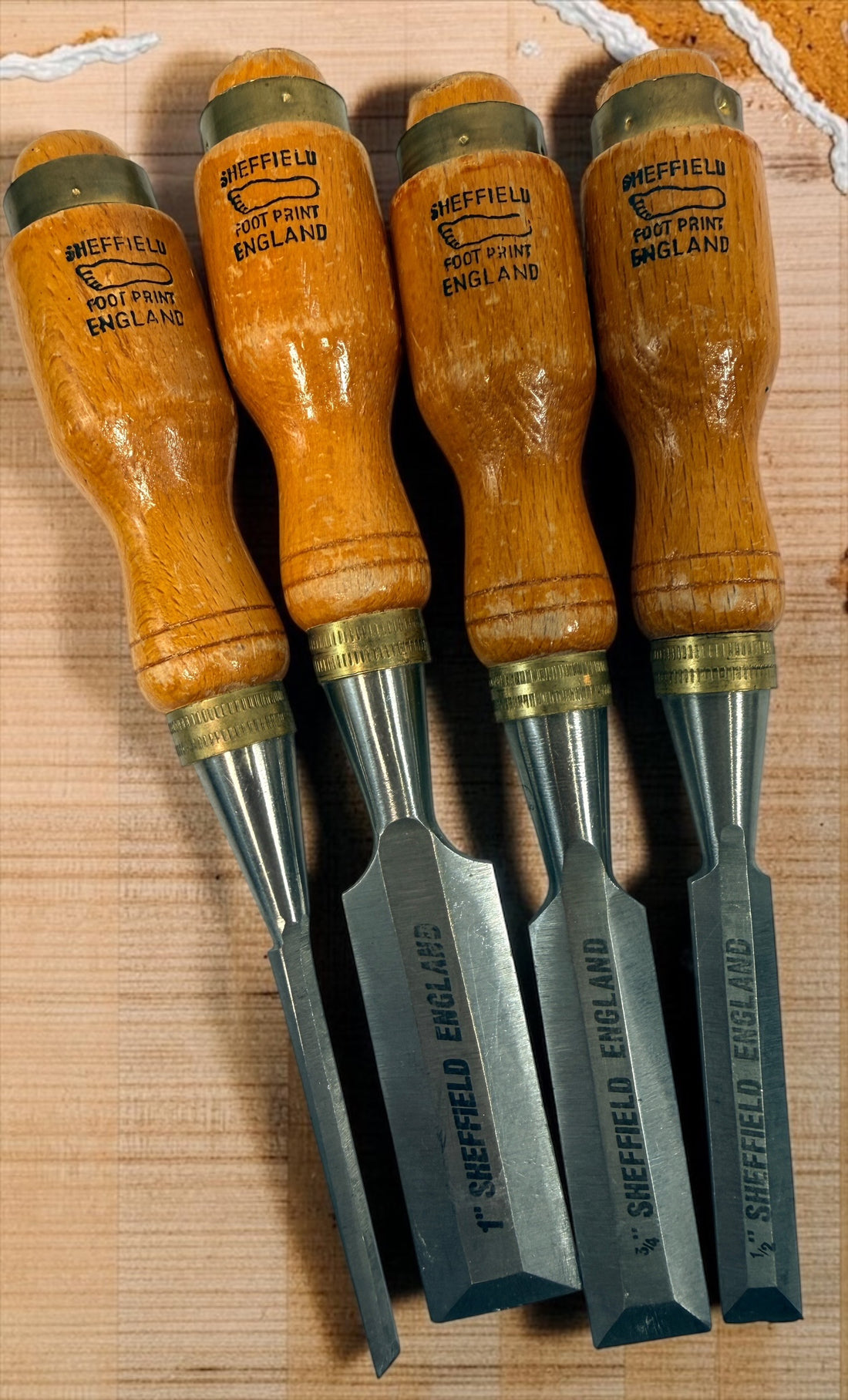 Vintage Footprint Sheffield England 4-piece woodworking chisel set with steel blades and hardwood handles. Classic British-made workshop tools.