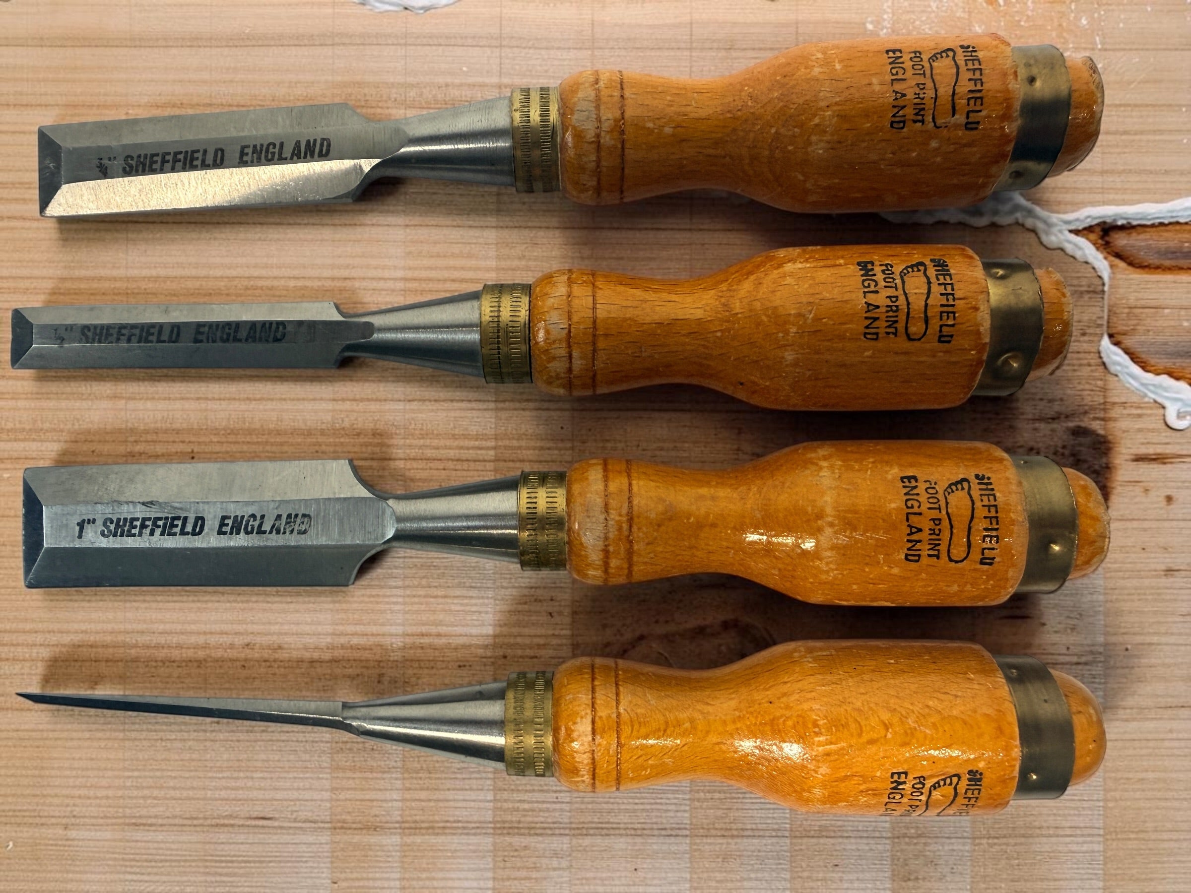 Vintage Footprint Sheffield England 4-piece woodworking chisel set with steel blades and hardwood handles. Classic British-made workshop tools.