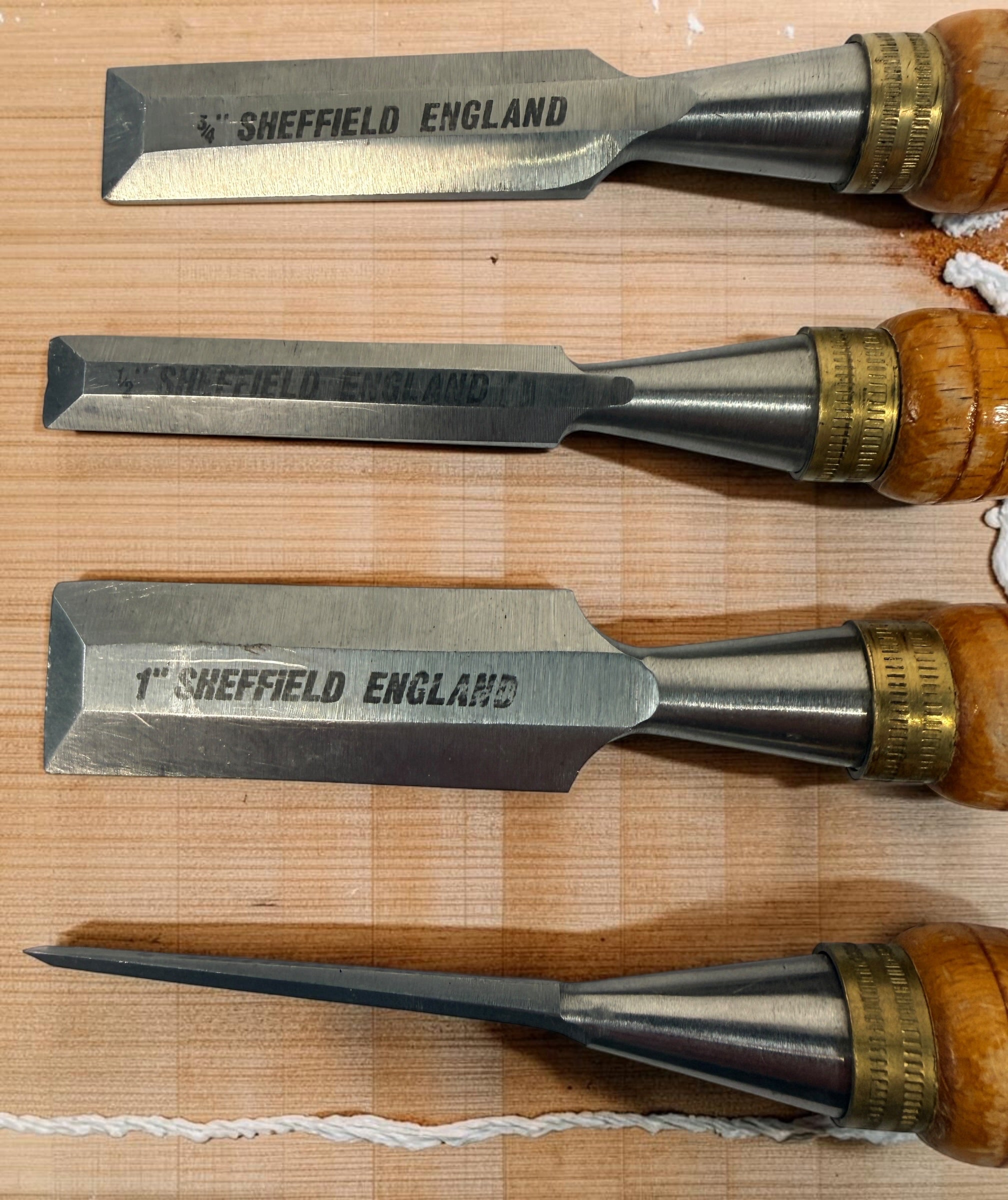 Vintage Footprint Sheffield England 4-piece woodworking chisel set with steel blades and hardwood handles. Classic British-made workshop tools.