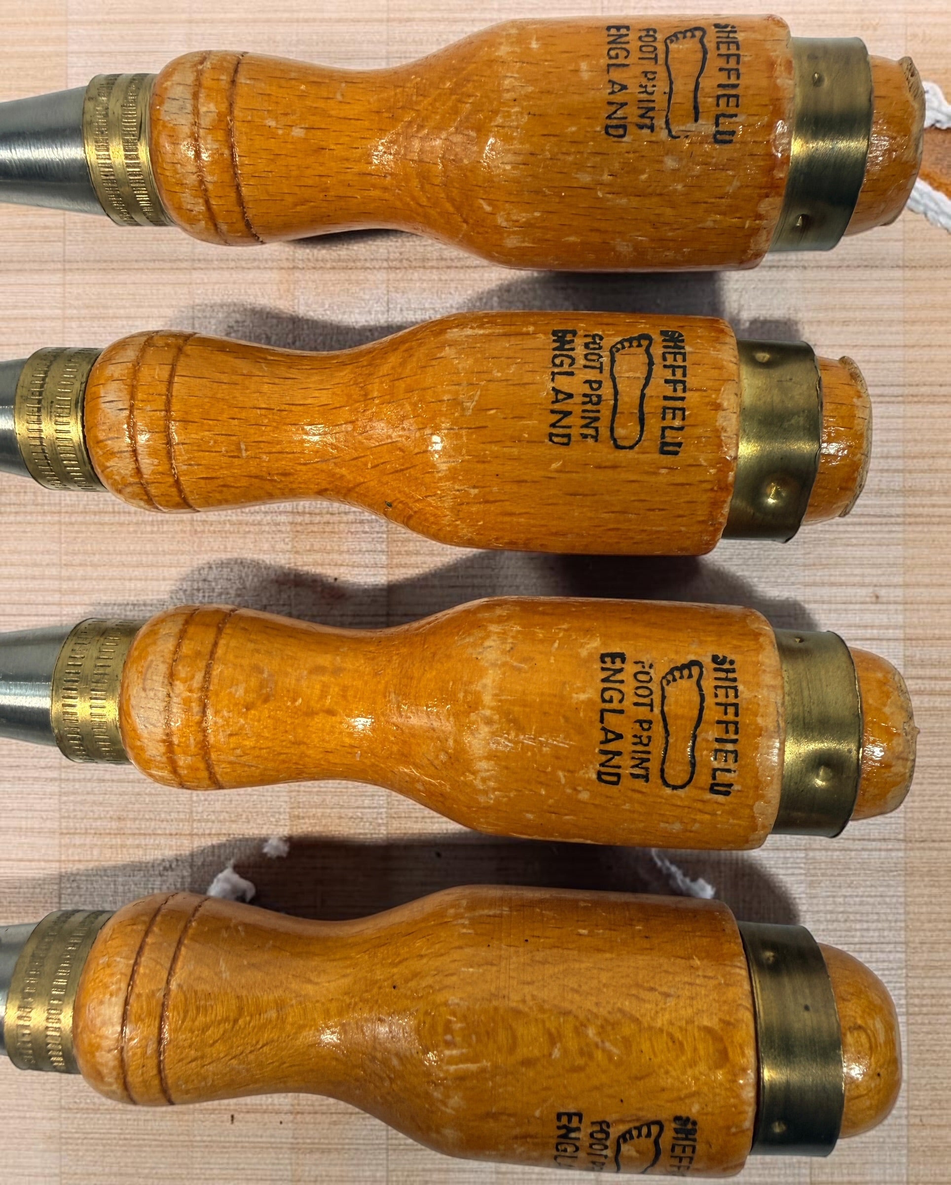 Vintage Footprint Sheffield England 4-piece woodworking chisel set with steel blades and hardwood handles. Classic British-made workshop tools.