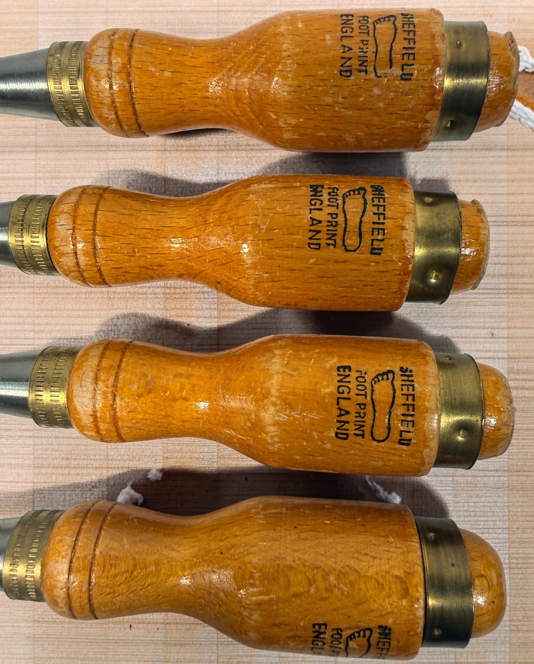 Vintage Footprint Sheffield England 4-piece woodworking chisel set with steel blades and hardwood handles. Classic British-made workshop tools.