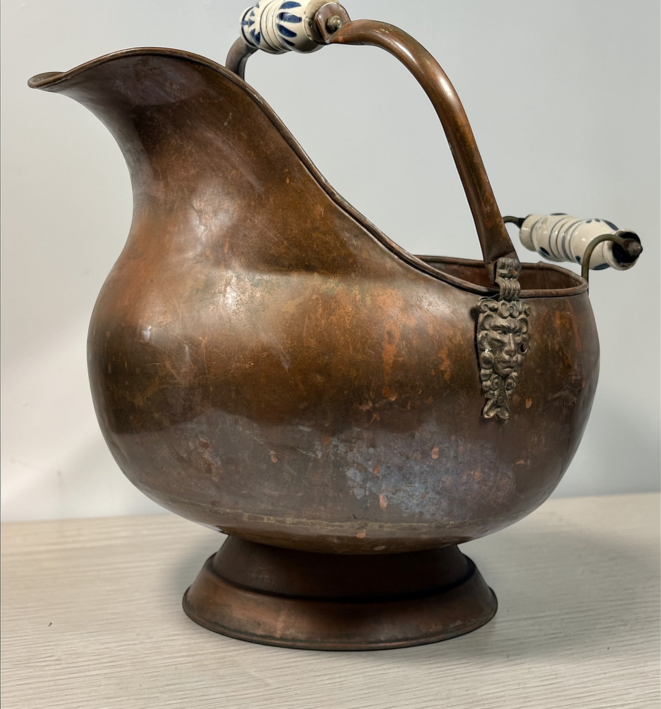Vintage copper coal scuttle with lion head handles and ceramic grips. Classic fireplace log bucket with rich patina, perfect for rustic or traditional décor. 🔥