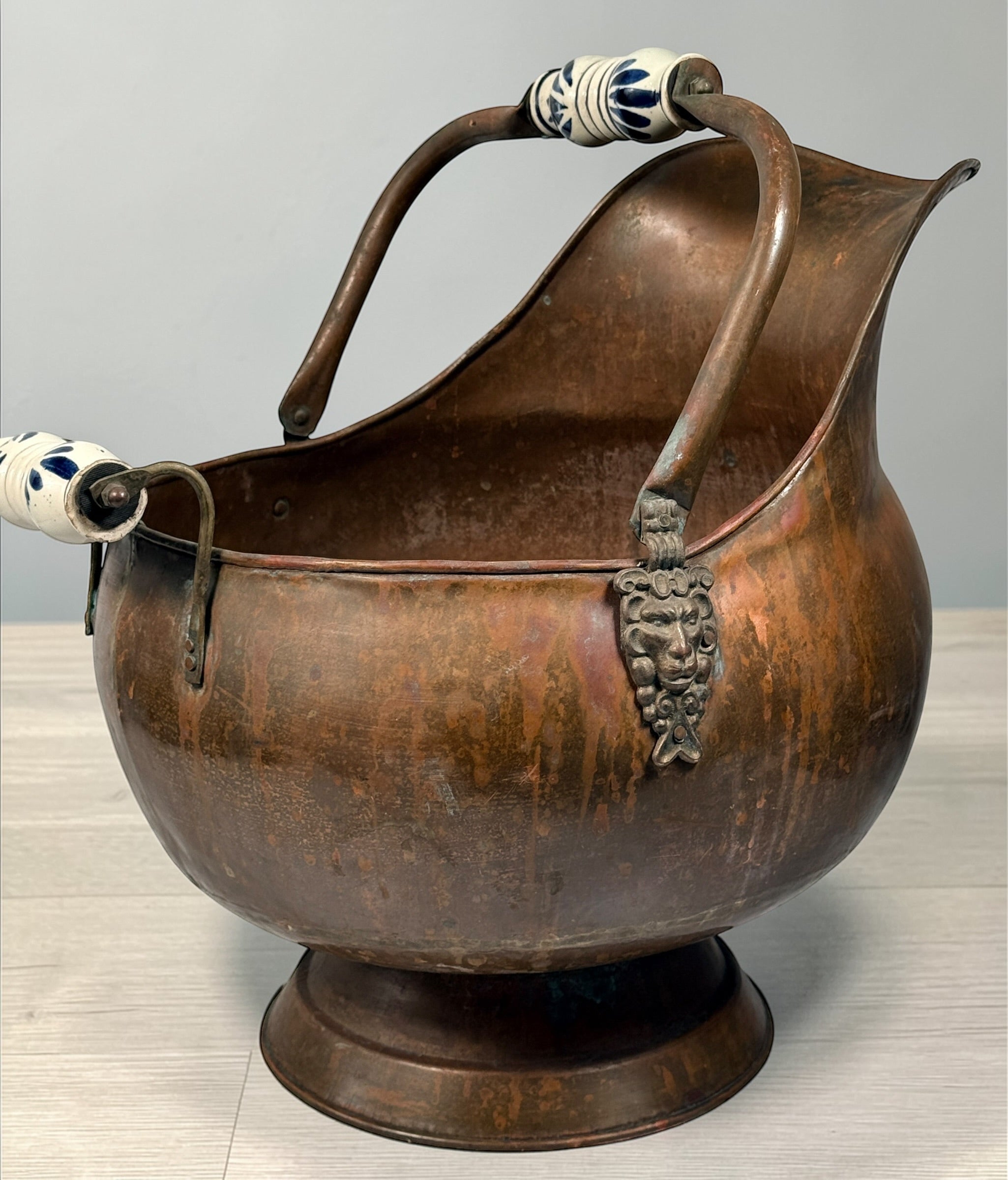 Vintage copper coal scuttle with lion head handles and ceramic grips. Classic fireplace log bucket with rich patina, perfect for rustic or traditional décor. 🔥