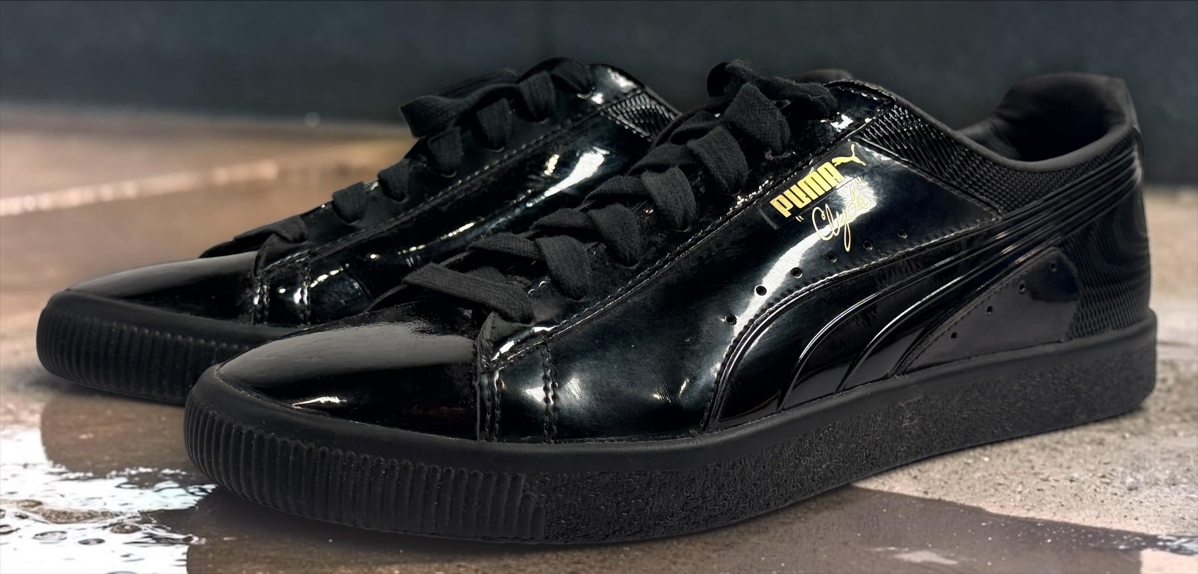 PUMA Clyde black patent-style men’s sneakers, US 10 / EU 43, featuring gold Clyde branding, tonal Formstrip and classic low-top styling.