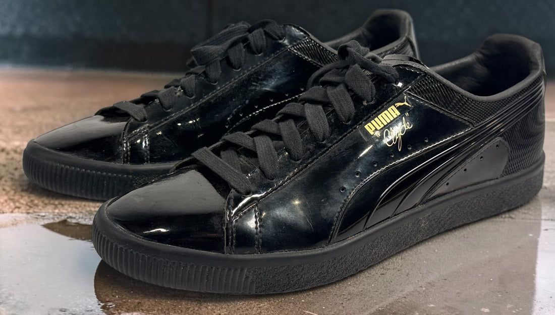 PUMA Clyde black patent-style men’s sneakers, US 10 / EU 43, featuring gold Clyde branding, tonal Formstrip and classic low-top styling.