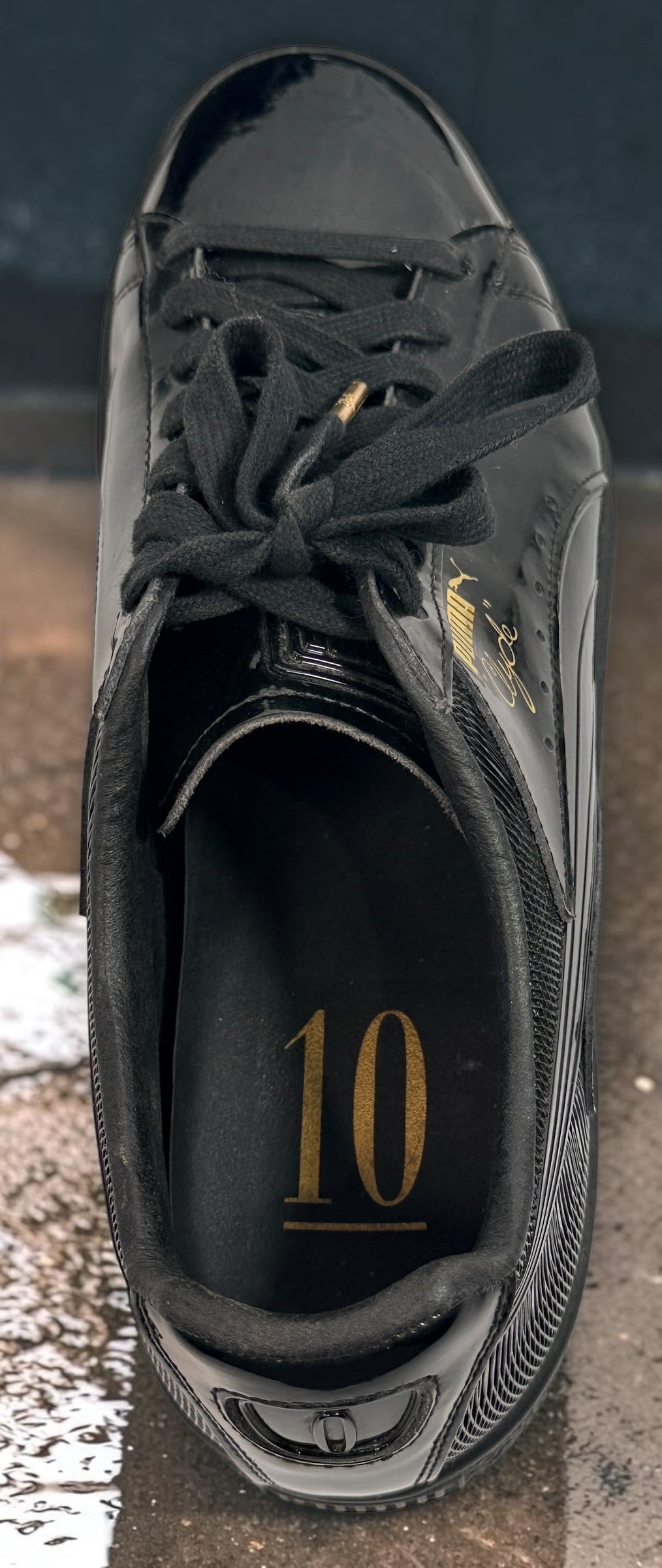 PUMA Clyde black patent-style men’s sneakers, US 10 / EU 43, featuring gold Clyde branding, tonal Formstrip and classic low-top styling.