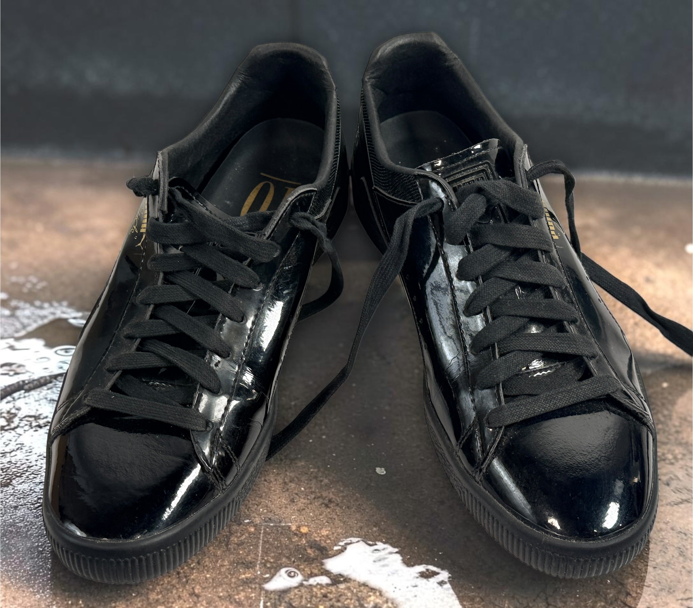 PUMA Clyde black patent-style men’s sneakers, US 10 / EU 43, featuring gold Clyde branding, tonal Formstrip and classic low-top styling.
