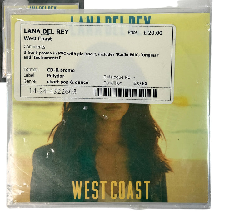 Lana Del Rey 'West Coast' CD-R promo single cover in clear plastic shrink wrap, with a white track information sticker overlaid on the front. The cover art features a yellow-green gradient background with a blurred portrait of Lana Del Rey and bold yellow 'WEST COAST' text at the bottom.