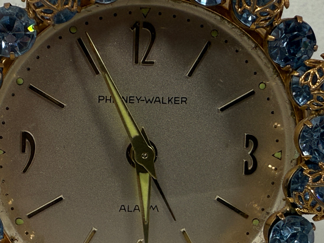 Close-up of a clock face with 'Phiney-Walker' branding and decorative blue gemstones.