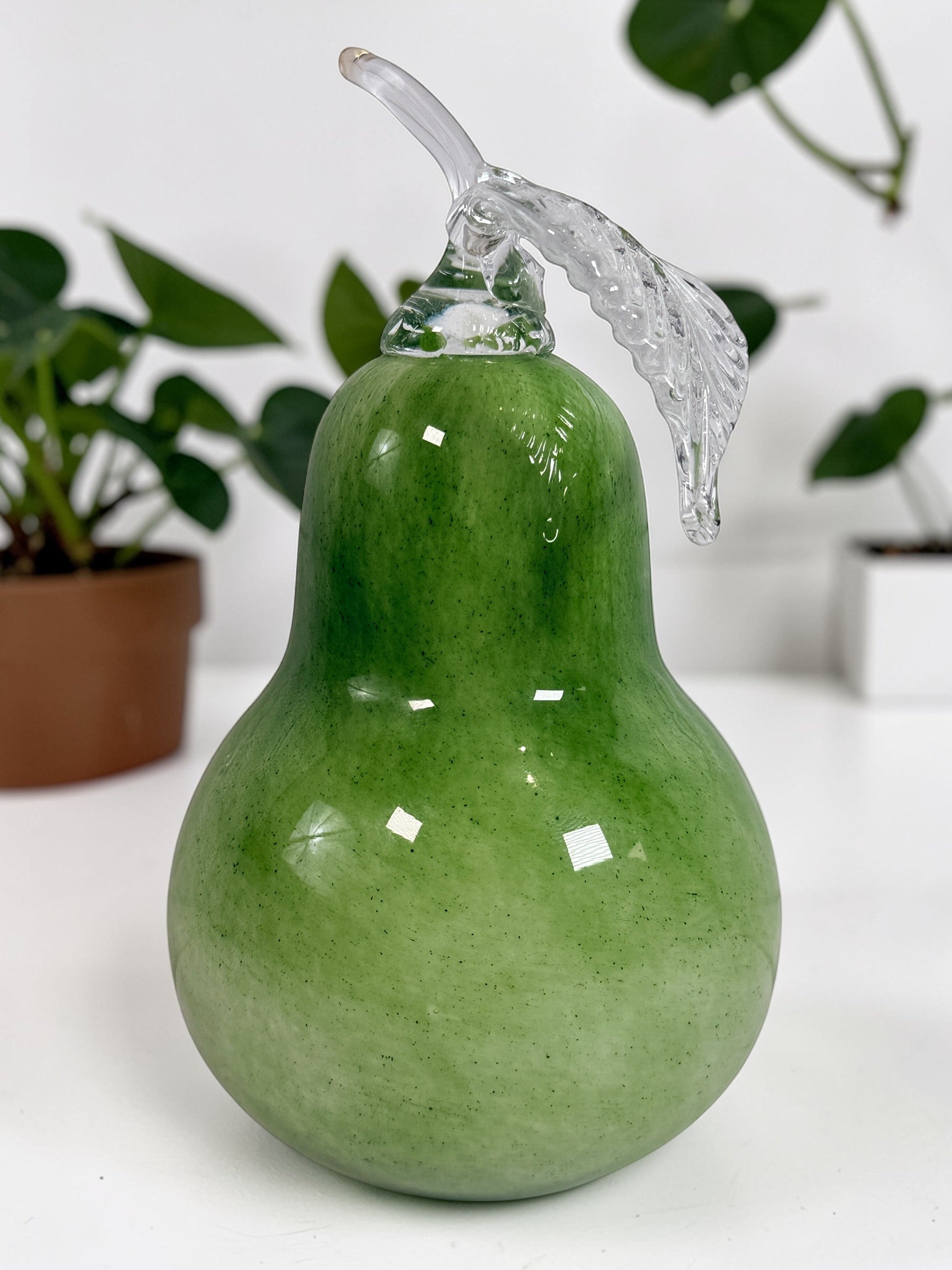 Vintage hand blown green art glass pear sculpture with clear leaf stem. Decorative Murano style glass fruit accent piece for kitchen or home décor.