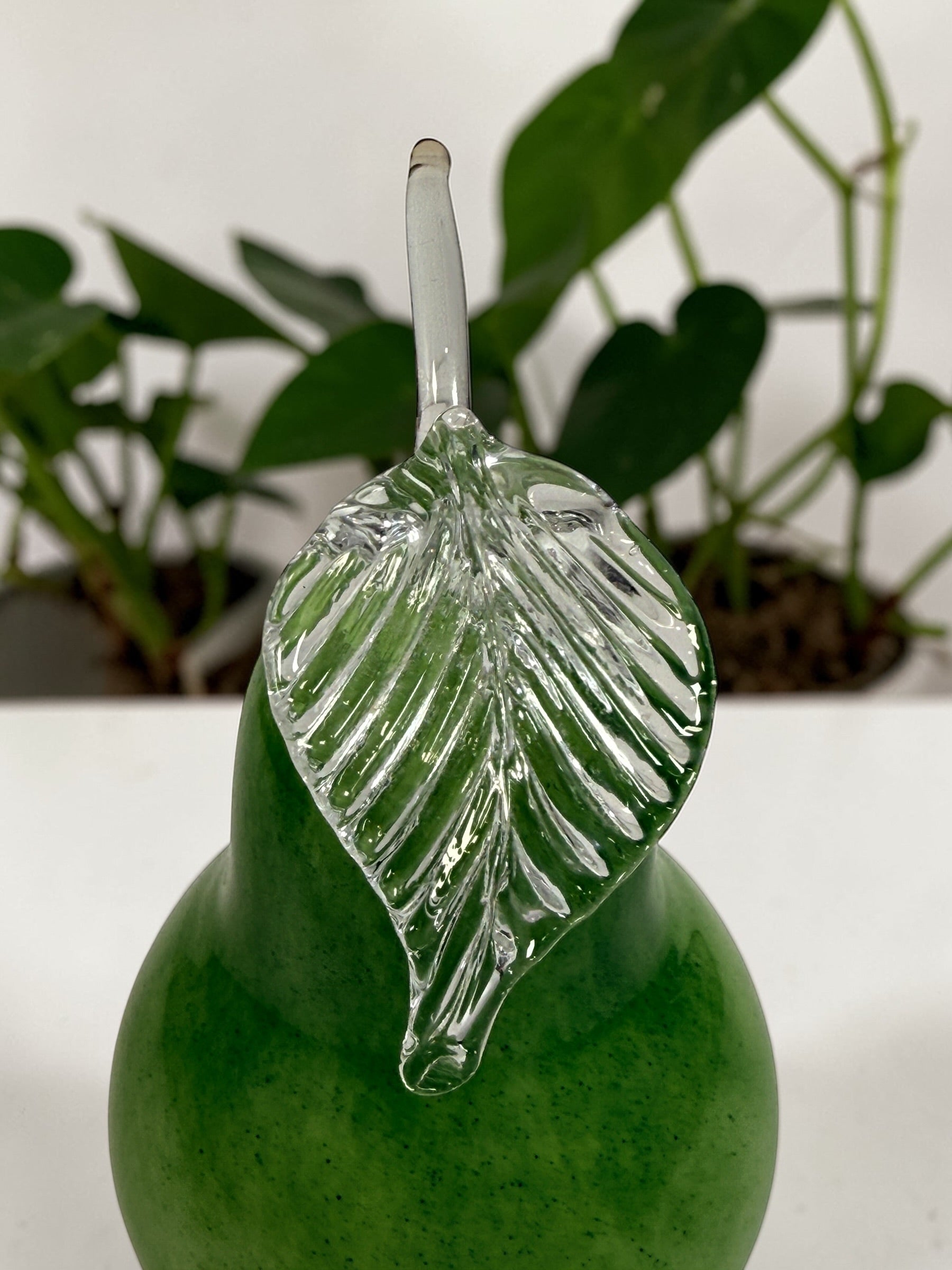Vintage hand blown green art glass pear sculpture with clear leaf stem. Decorative Murano style glass fruit accent piece for kitchen or home décor.