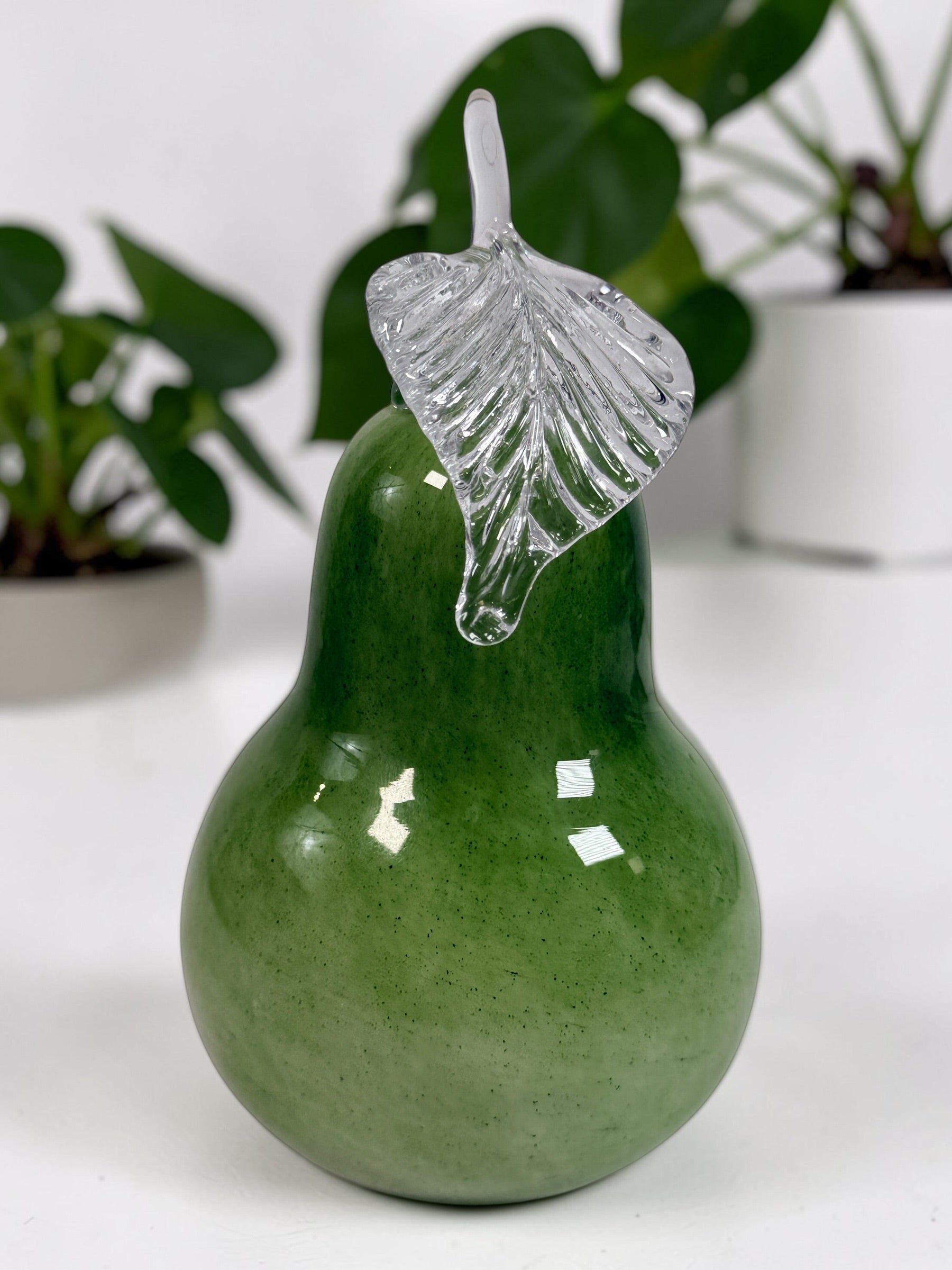 Vintage hand blown green art glass pear sculpture with clear leaf stem. Decorative Murano style glass fruit accent piece for kitchen or home décor.