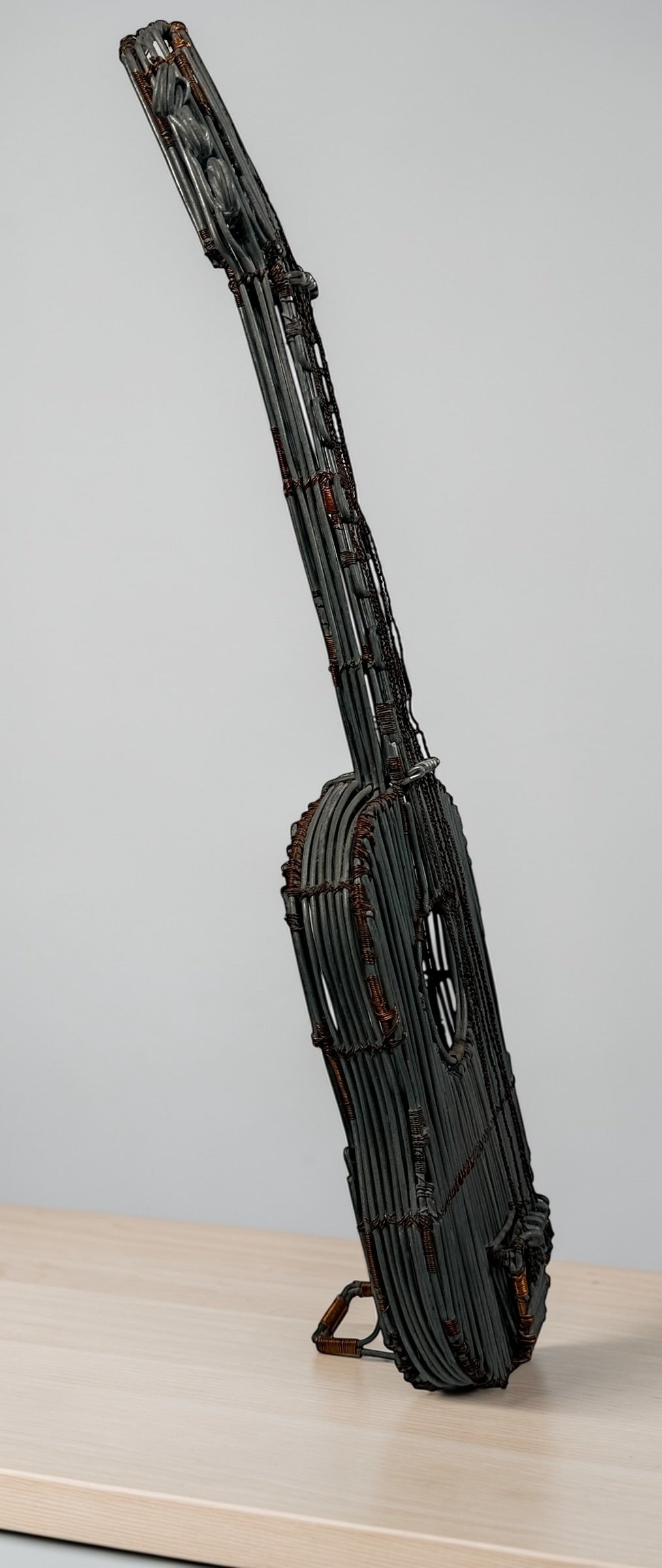 Vintage handmade wire guitar sculpture crafted from steel and copper. Industrial folk art decor piece with freestanding stand, perfect for music room or studio display.
