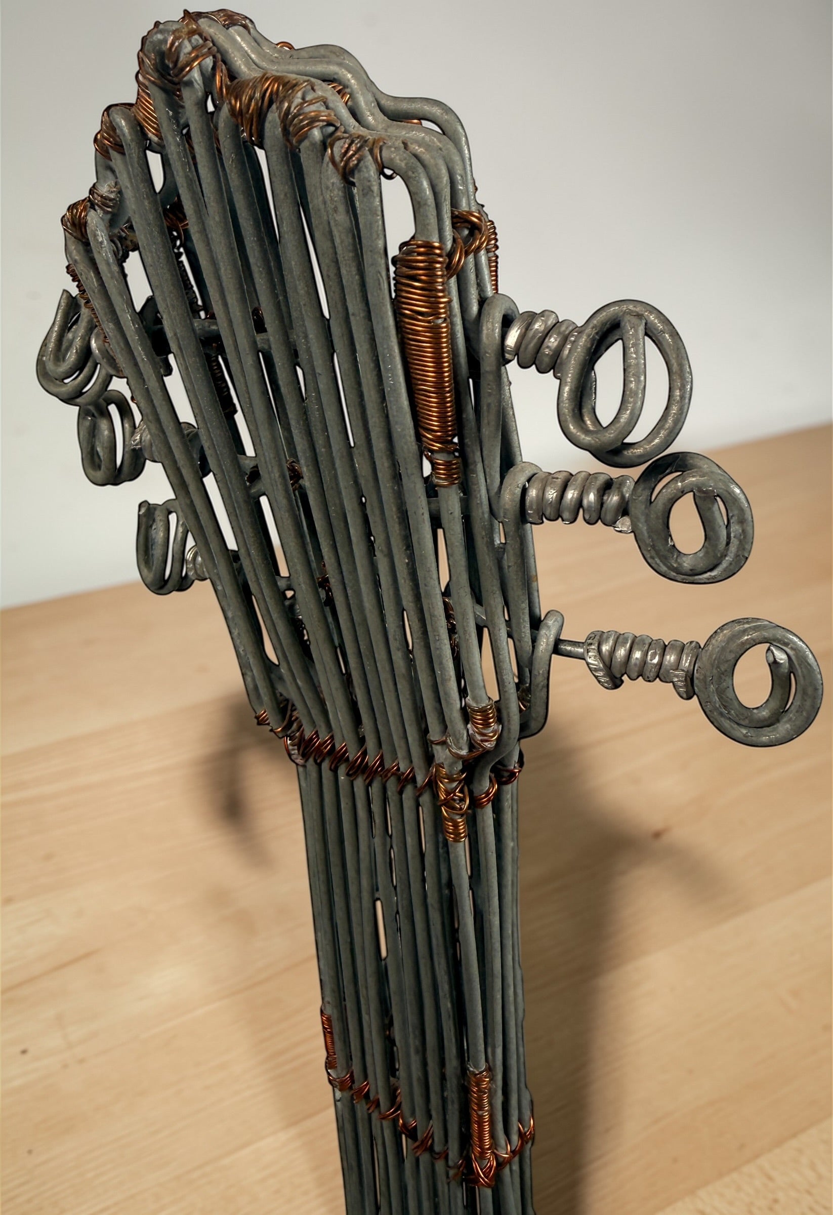Vintage handmade wire guitar sculpture crafted from steel and copper. Industrial folk art decor piece with freestanding stand, perfect for music room or studio display.