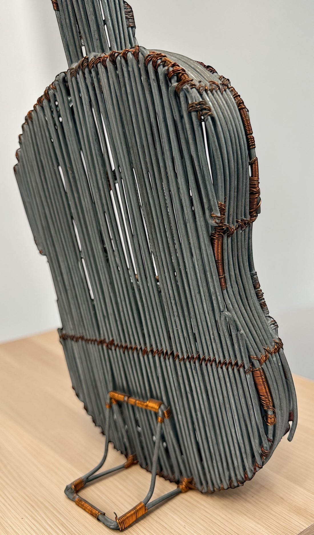 Vintage handmade wire guitar sculpture crafted from steel and copper. Industrial folk art decor piece with freestanding stand, perfect for music room or studio display.